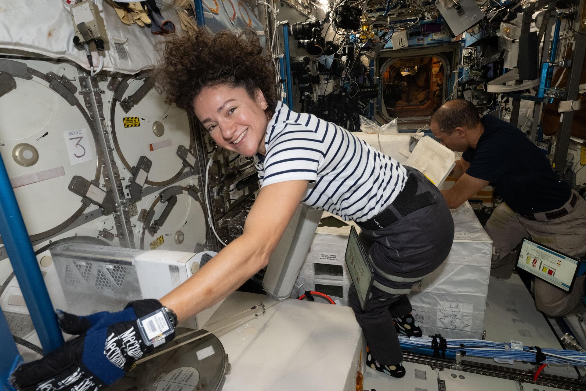Expedition 74 Flight Engineers Jessica Meir and Chris Williams, both NASA astronauts, collect frozen research samples from inside the International Space Station's Destiny laboratory module. The samples were stowed inside science freezers aboard a SpaceX Dragon spacecraft for retrieval and analysis on Earth.