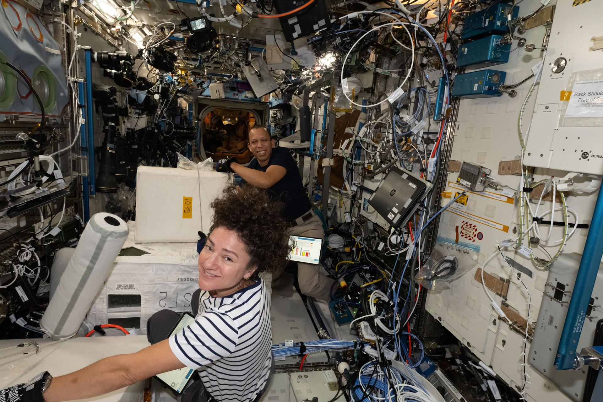 Expedition 74 Flight Engineers Jessica Meir and Chris Williams, both NASA astronauts, collect frozen research samples from inside the International Space Station's Destiny laboratory module. The samples were stowed inside science freezers aboard a SpaceX Dragon spacecraft for retrieval and analysis on Earth.