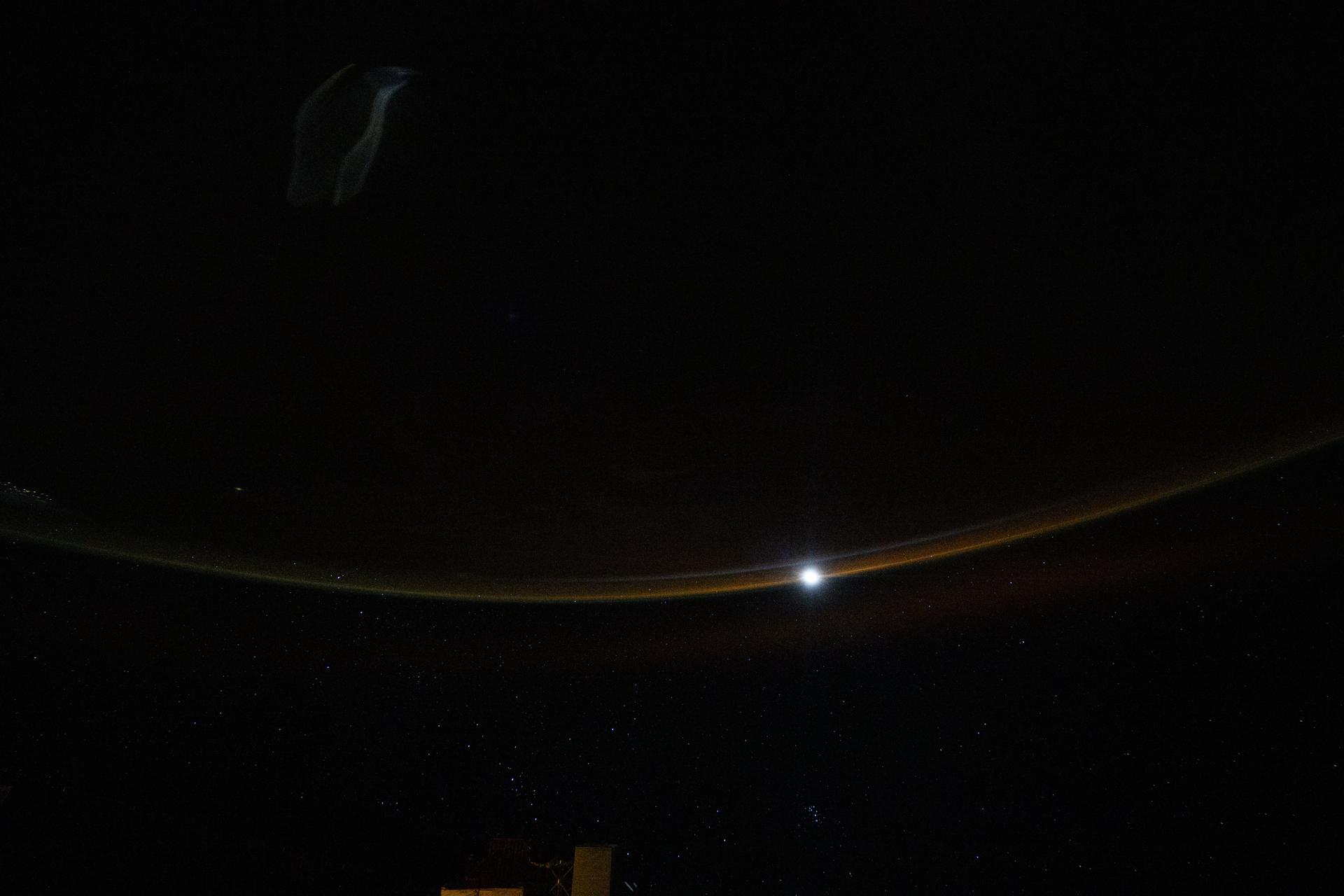 A dim airglow blankets Earth’s horizon as a faint Moon sets above a dark and vast Indian Ocean in this photograph from the International Space Station, which was orbiting 264 miles above the Maldives—an Asian archipelago nation southwest of India—at approximately 12:11 a.m. local time.