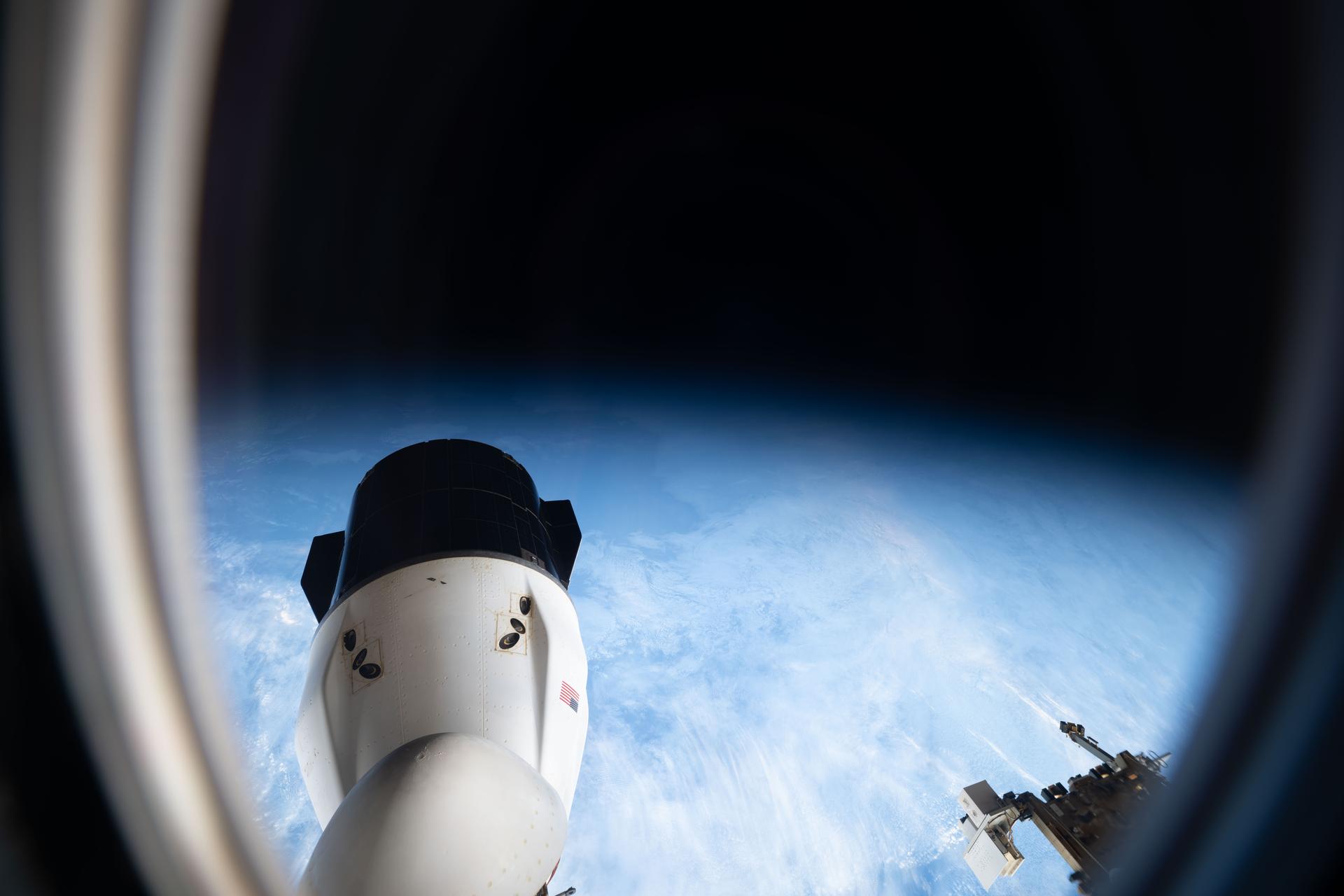 Peering out a window of a SpaceX Dragon spacecraft toward another Dragon spacecraft, the International Space Station soars into an orbital sunset 274 miles above the South Atlantic Ocean.