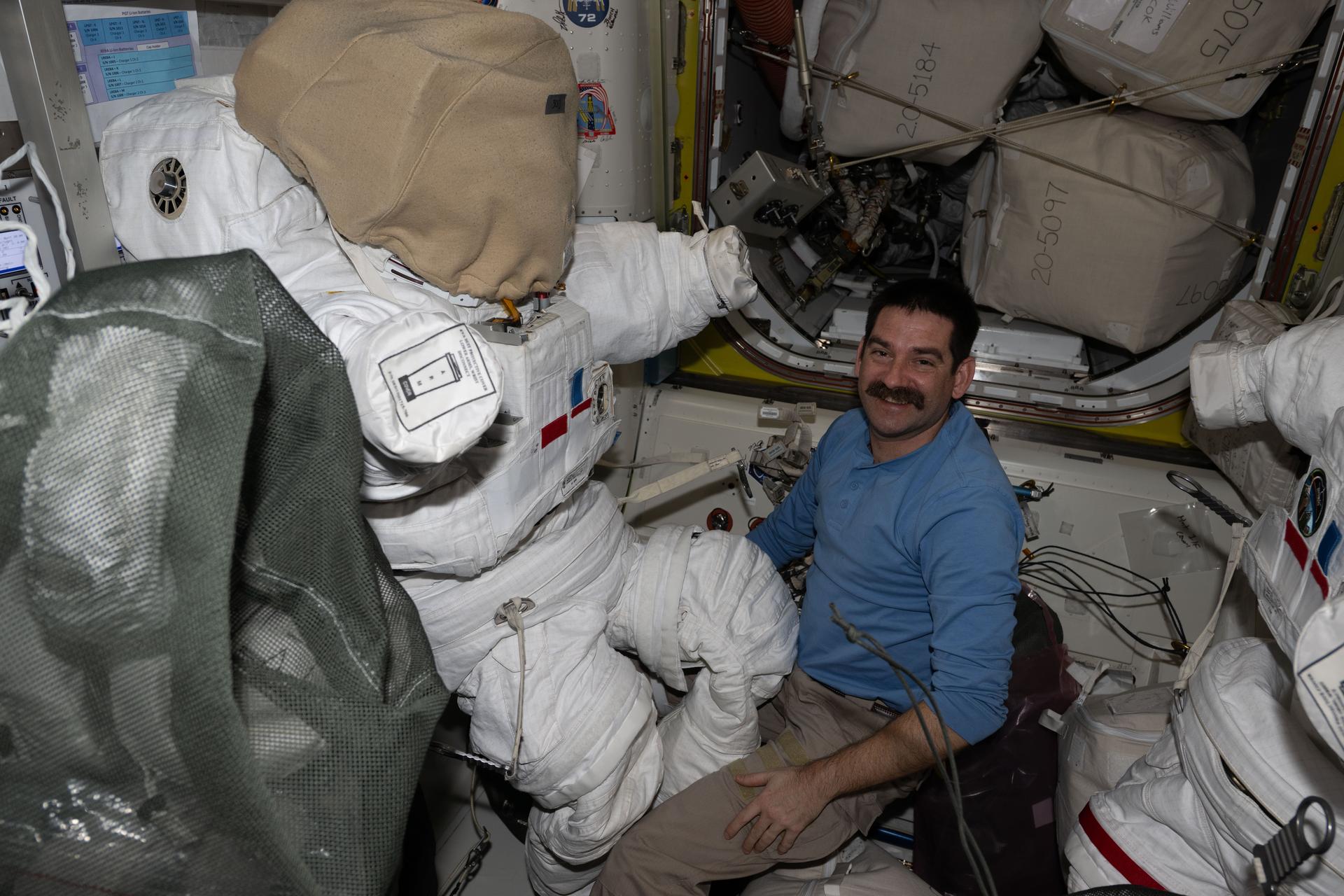 NASA astronaut and Expedition 74 flight engineer Jack Hathaway configures a spacesuit installing its components, checking a helmet, and cleaning suit seals inside the International Space Station's Quest airlock.