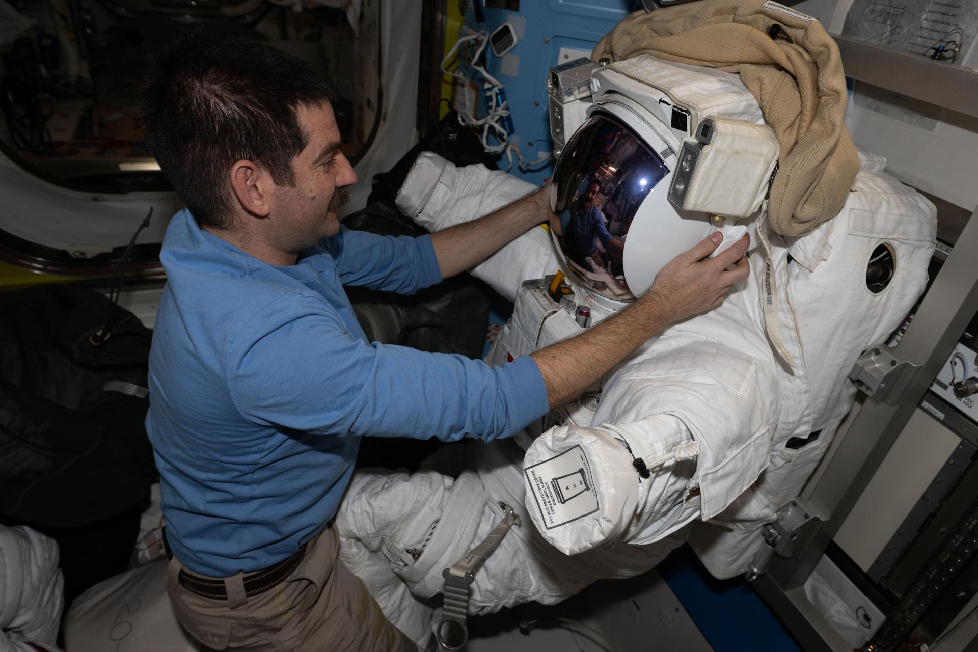 NASA astronaut and Expedition 74 flight engineer Jack Hathaway configures a spacesuit installing its components, checking a helmet, and cleaning suit seals inside the International Space Station's Quest airlock.