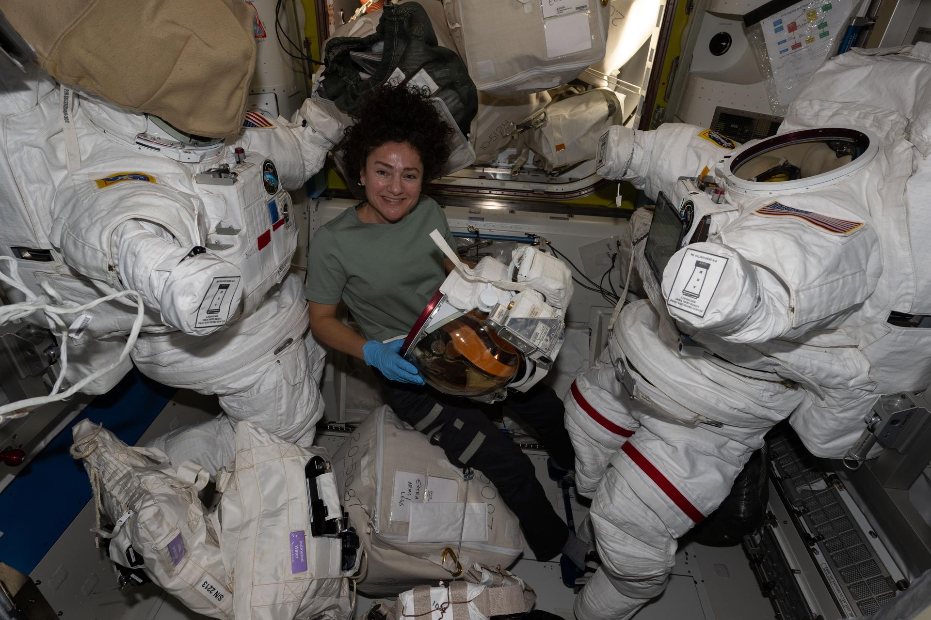 NASA astronaut and Expedition 74 flight engineer Jessica Meir smiles for a portrait while preparing a helmet for installation on a spacesuit inside the International Space Station's Quest airlock.