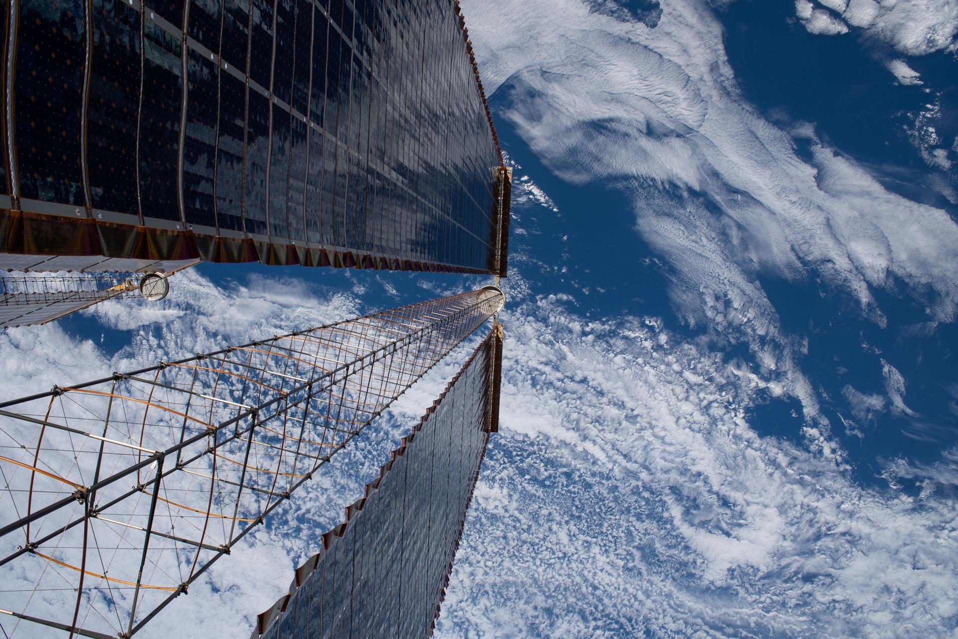 A view peering down a pair of the International Space Station's roll-out solar arrays, photographed during a spacewalk conducted on March 18, 2026 to build and install a modification kit ahead of future solar array installation on the 2A power channel of the space station.