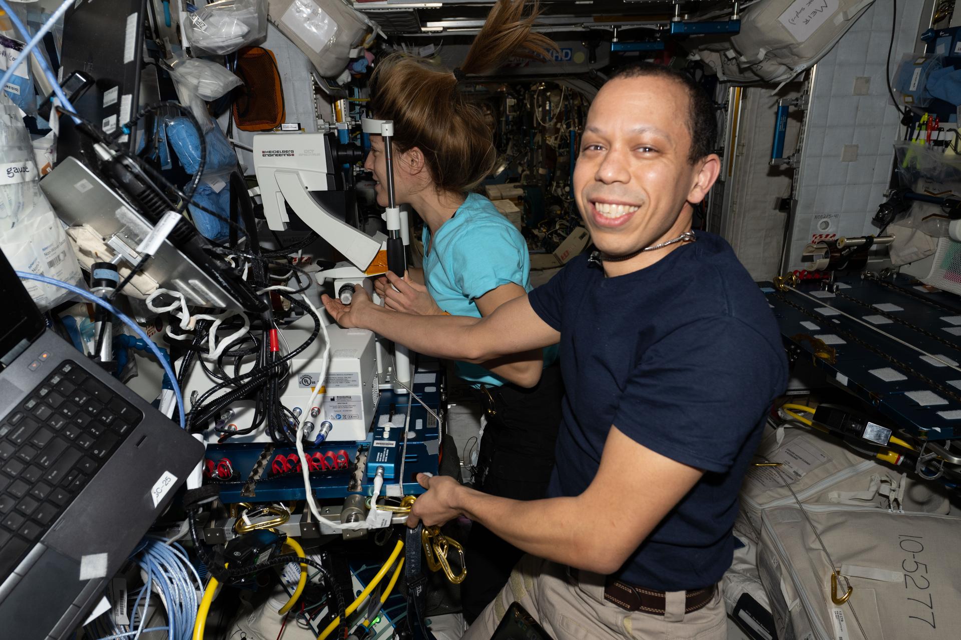 NASA astronaut Chris Williams smiles for a portrait while guiding ESA (European Space Agency) astronaut Sophie Adenot as she peers into an Optical Coherence Tomography machine, a medical imaging device used for eye exams. Doctors on the ground monitored in real-time viewing her retina, lens, and cornea. Vision is critical to a mission’s success and doctors regularly check the astronauts’ eyes to counteract the potential effects of living in space.