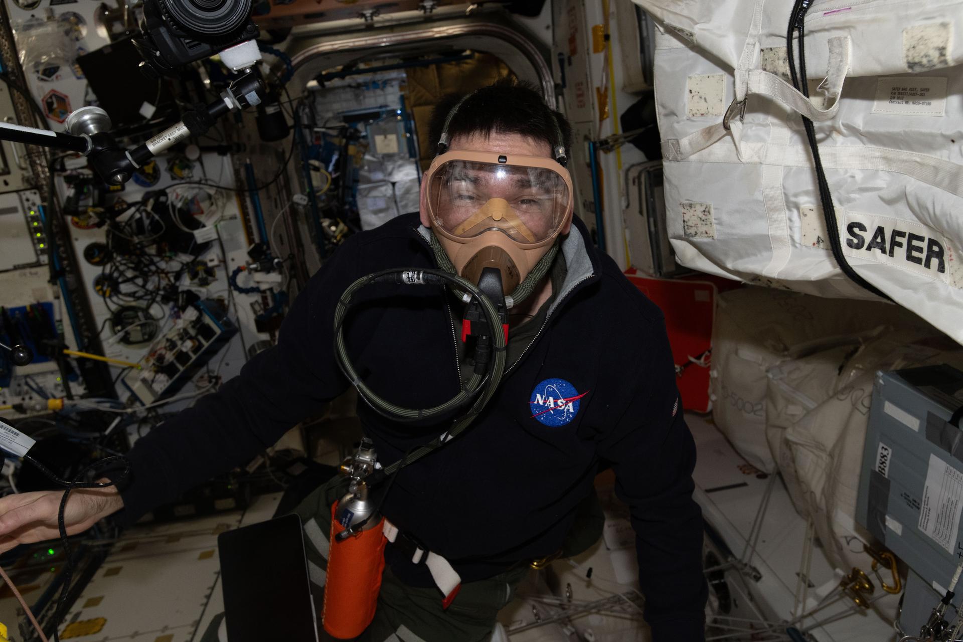 NASA astronaut and Expedition 74 flight engineer Jack Hathaway is wearing a portable breathing apparatus to test its readiness for unlikely emergency scenarios such as an oxygen leak, chemical leak, or fire aboard the orbital outpost.