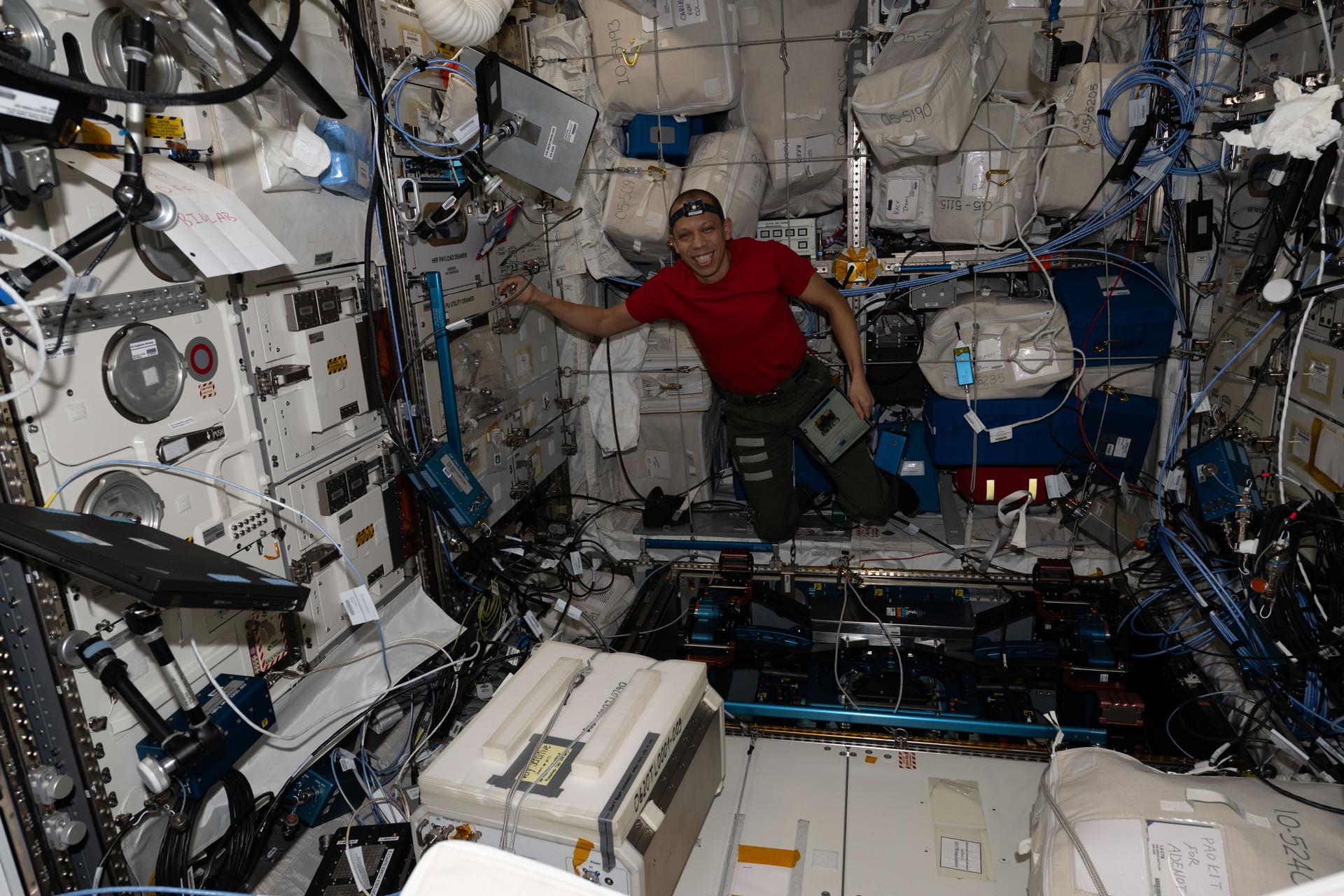 NASA astronaut and Expedition 74 flight engineer Chris Williams unpacks computer hardware that supports the European Enhanced Exploration Exercise Device, or E4D, preparing it for installation and activation inside the International Space Station's Columbus laboratory module. The E4D was delivered on Northrop Grumman’s second Cygnus XL cargo mission and will be evaluated for its ability to support crew workouts on missions to the Moon, Mars, and beyond.