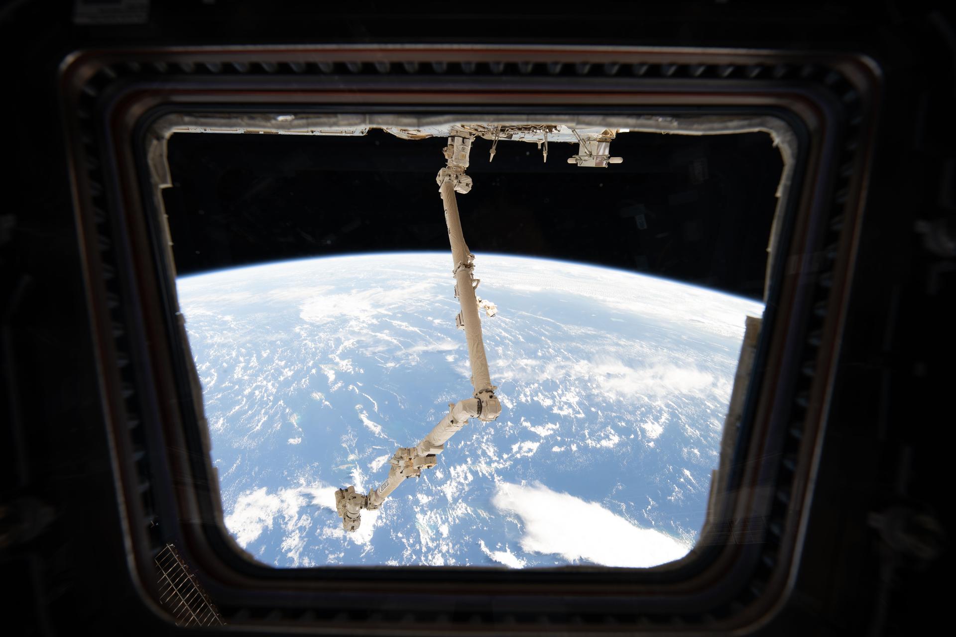 This view from a window in the International Space Station’s cupola highlights the 57.7‑foot‑long Canadarm2 robotic arm attached to a power‑and‑data grapple fixture on the Harmony module. The orbital outpost was soaring 264 miles above the Atlantic Ocean northwest of Puerto Rico at the time of this photograph.