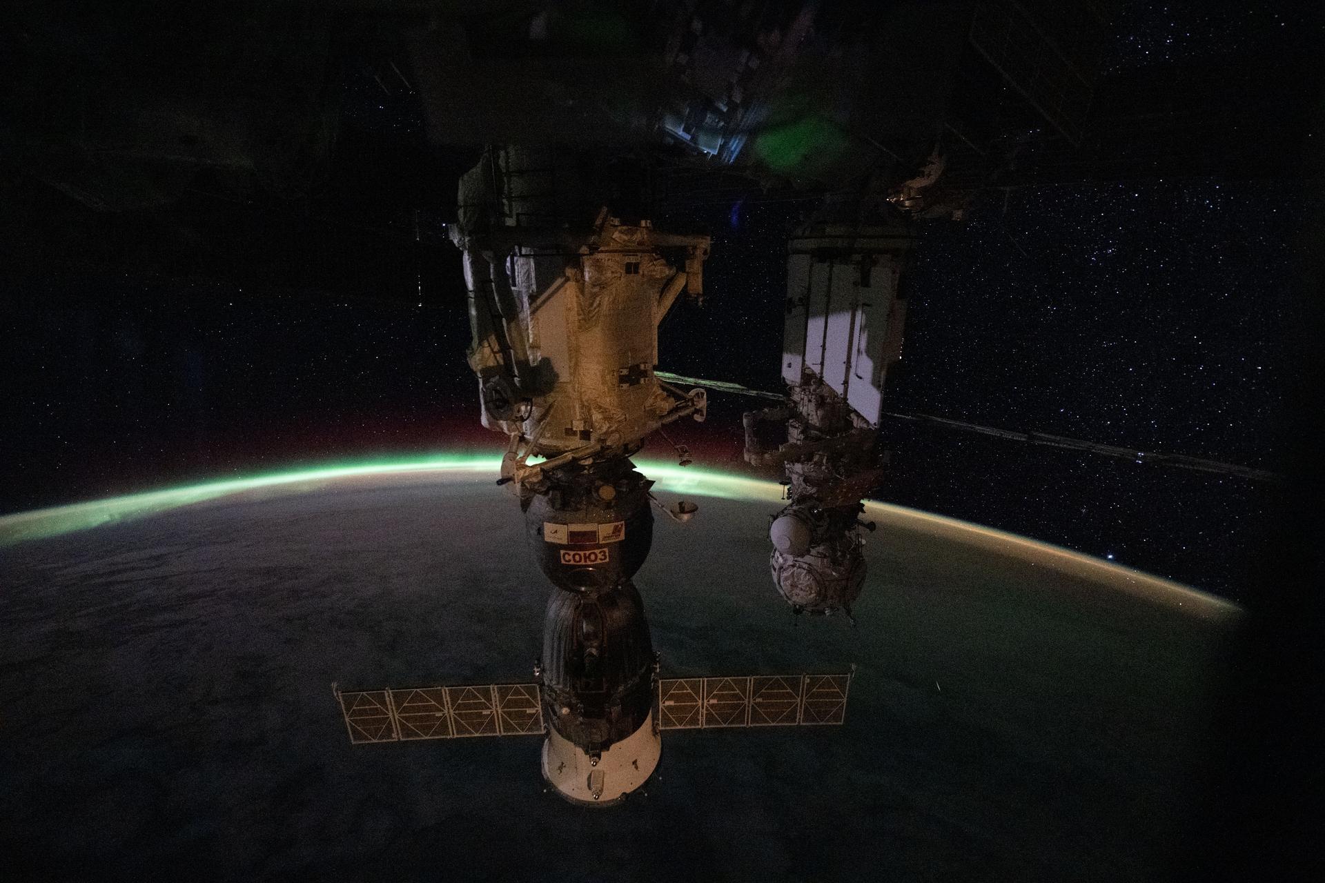 iss074e0504006 (April 12, 2026) --- The aurora australis arcs above Earth’s horizon and fades into the airglow as the International Space Station orbited 265 miles above the Indian Ocean east of Perth, Australia, at approximately 2:03 a.m. local time. In the foreground, the Soyuz MS-28 crew spacecraft is shown docked to the Rassvet module. In the background, the Pirs docking module is attached to the Nauka science module. Credit: NASA/Chris Williams