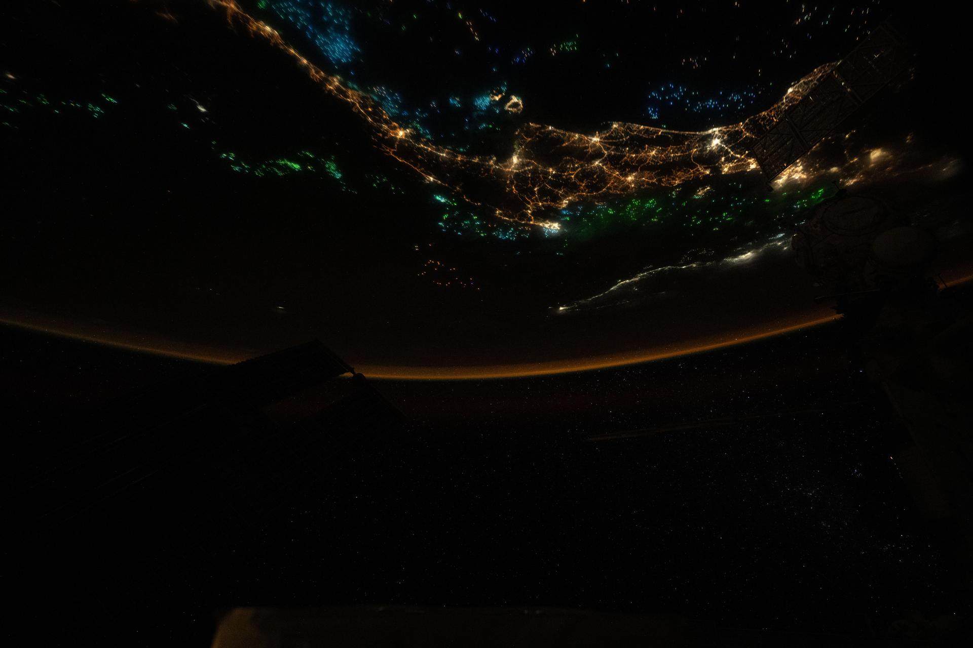 The blue and green lights of fishing boats dot the Gulf of Thailand and the Andaman Sea surrounding the city lights of the Malay Peninsula. The lights attract and illuminate plankton and small fish, luring squid toward the boats’ fishing nets. This photograph was taken at approximately 1:48 a.m. local time from the International Space Station as it orbited 259 miles above Earth.