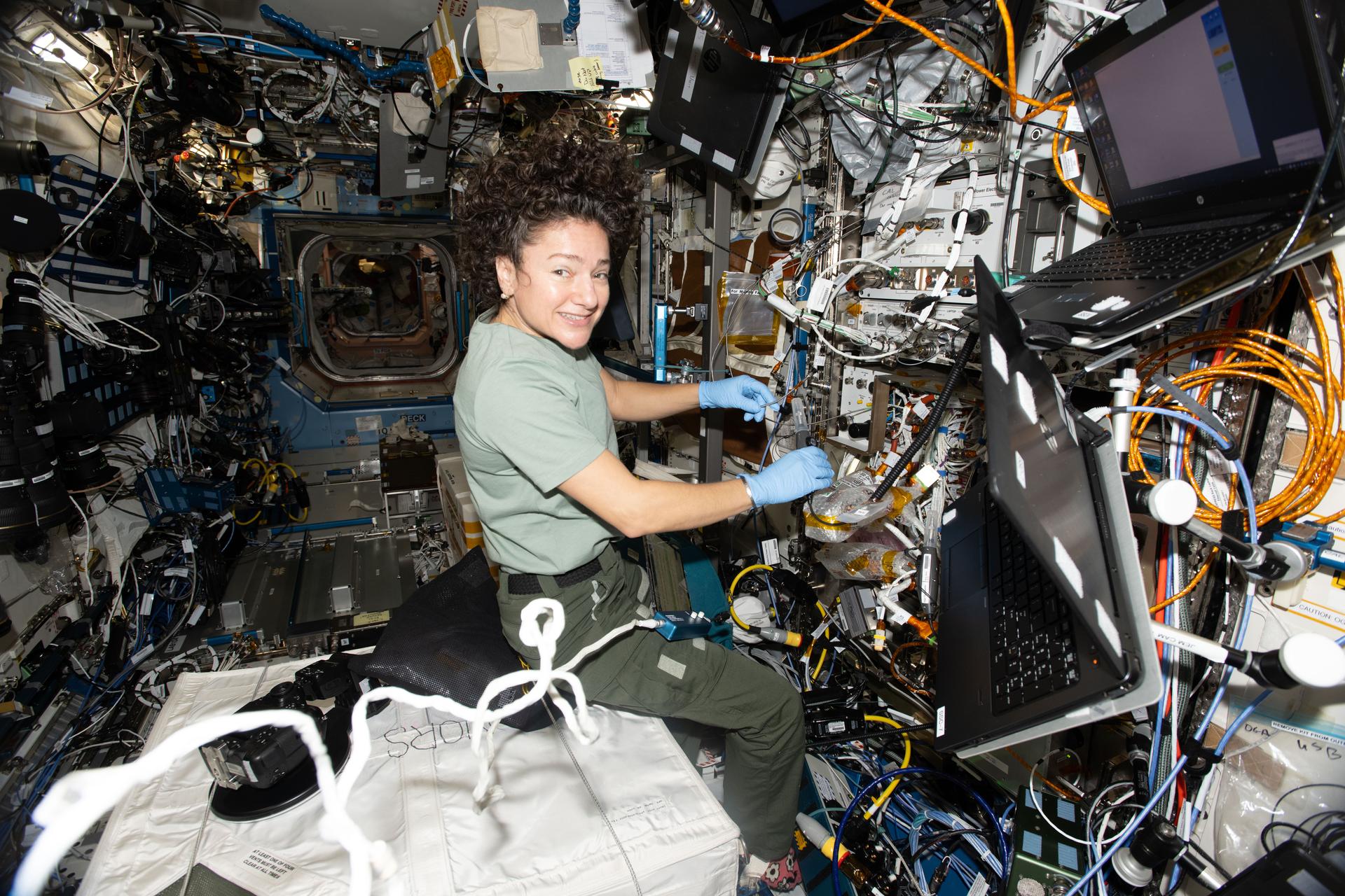 NASA astronaut and Expedition 74 flight engineer Jessica Meir inspects sensitive fiber cables that emit light to help cool, trap, and study atoms with high accuracy inside the Cold Atom Lab (CAL) aboard the International Space Station. The CAL, a quantum research facility, chills atoms to near absolute zero, providing insights into atomic wave functions, general relativity, and dark matter.