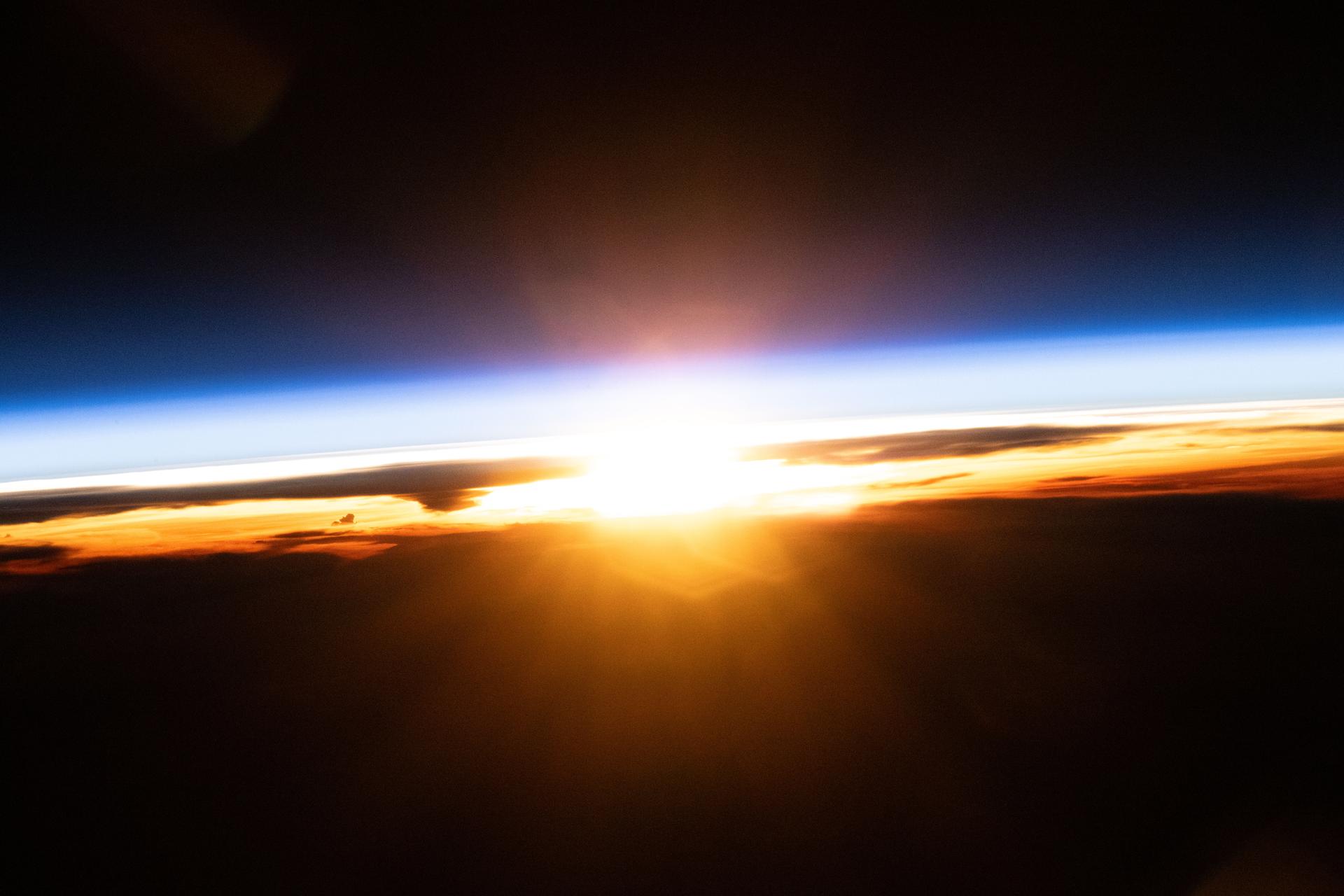 The last rays of an orbital sunset illuminate Earth's atmosphere and the cloud tops in this photograph from the International Space Station as it orbited 258 miles above the Pacific Ocean north of Papua New Guinea.