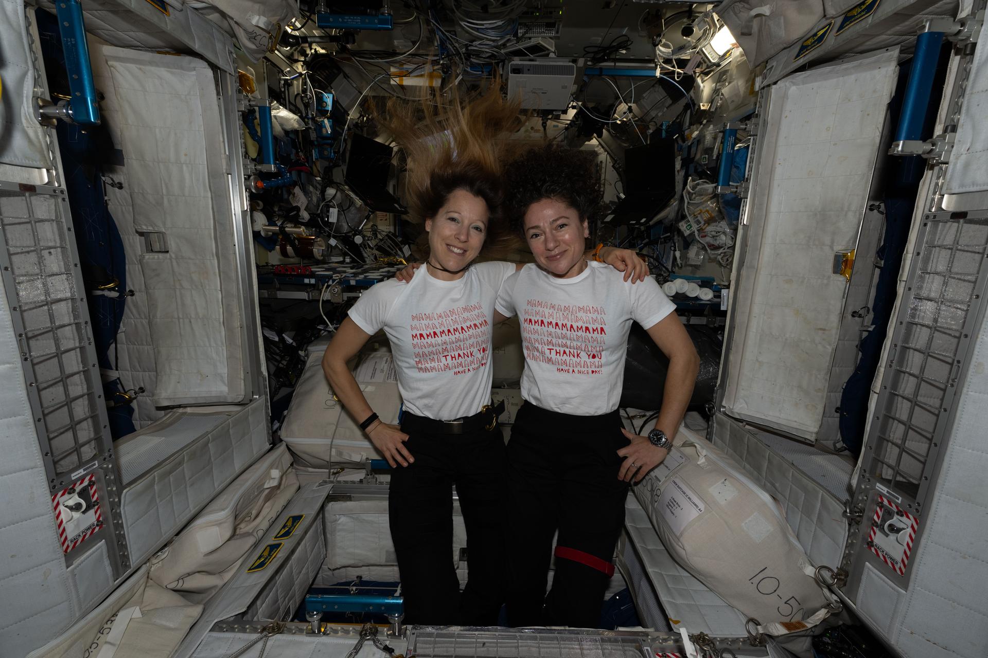 From left, Expedition 74 flight engineers Sophie Adenot of ESA (European Space Agency) and Jessica Meir of NASA pose for a portrait inside the International Space Station’s Harmony module on Mother’s Day. Adenot, who has a son, and Meir, who has a daughter, wrap their arms around each other’s shoulders and wear T‑shirts celebrating motherhood.