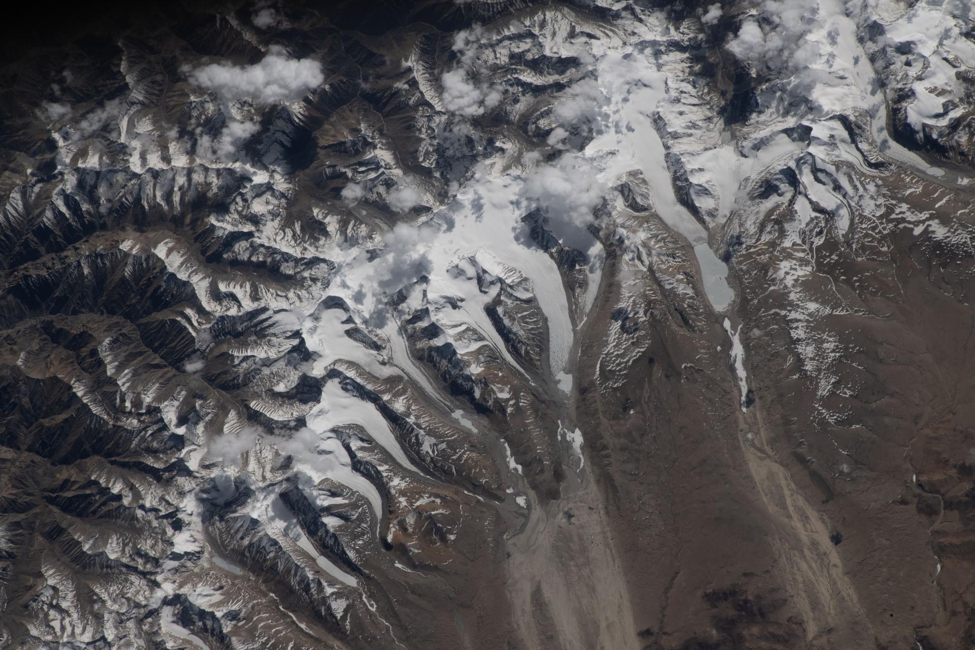 The Himalayas separate Nepal from China in this photograph from the International Space Station as it orbited 259 miles above the western Tibetan Plateau. Glaciers—slow‑moving rivers of ice that carve paths into mountainsides—flow downhill from the Himalayas’ northern slopes onto China's Tibetan Plateau.