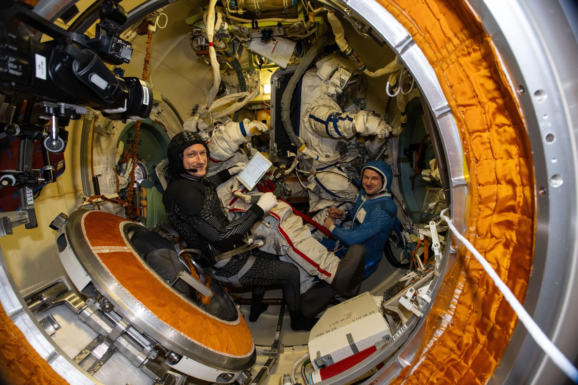 Roscosmos cosmonauts Sergey Kud-Sverchkov and Sergei Mikaev, Expedition 74 commander and flight engineer respectively, are pictured inside the Poisk module's airlock preparing to try on their Orlan spacesuits. The duo was preparing for a spacewalk to install a solar radiation experiment and remove biological exposure hardware on the outside of the International Space Station.