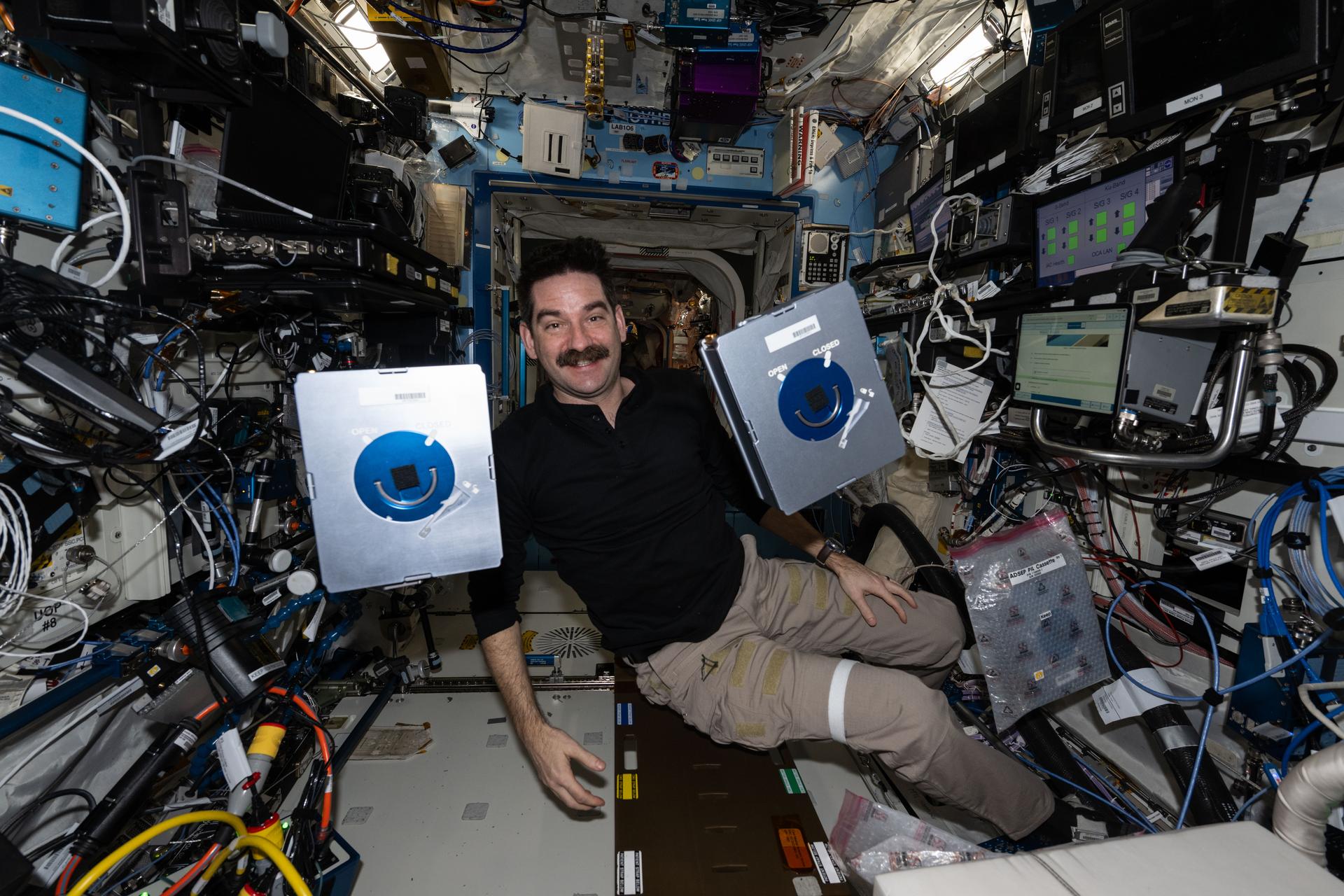 NASA astronaut and Expedition 74 flight engineer Jack Hathaway shows off a pair of Advanced Space Experiment Sample Processor-4 research cassettes being used aboard the International Space Station to study how weightlessness affects drug crystals possibly leading to new pharmaceutical formulas.