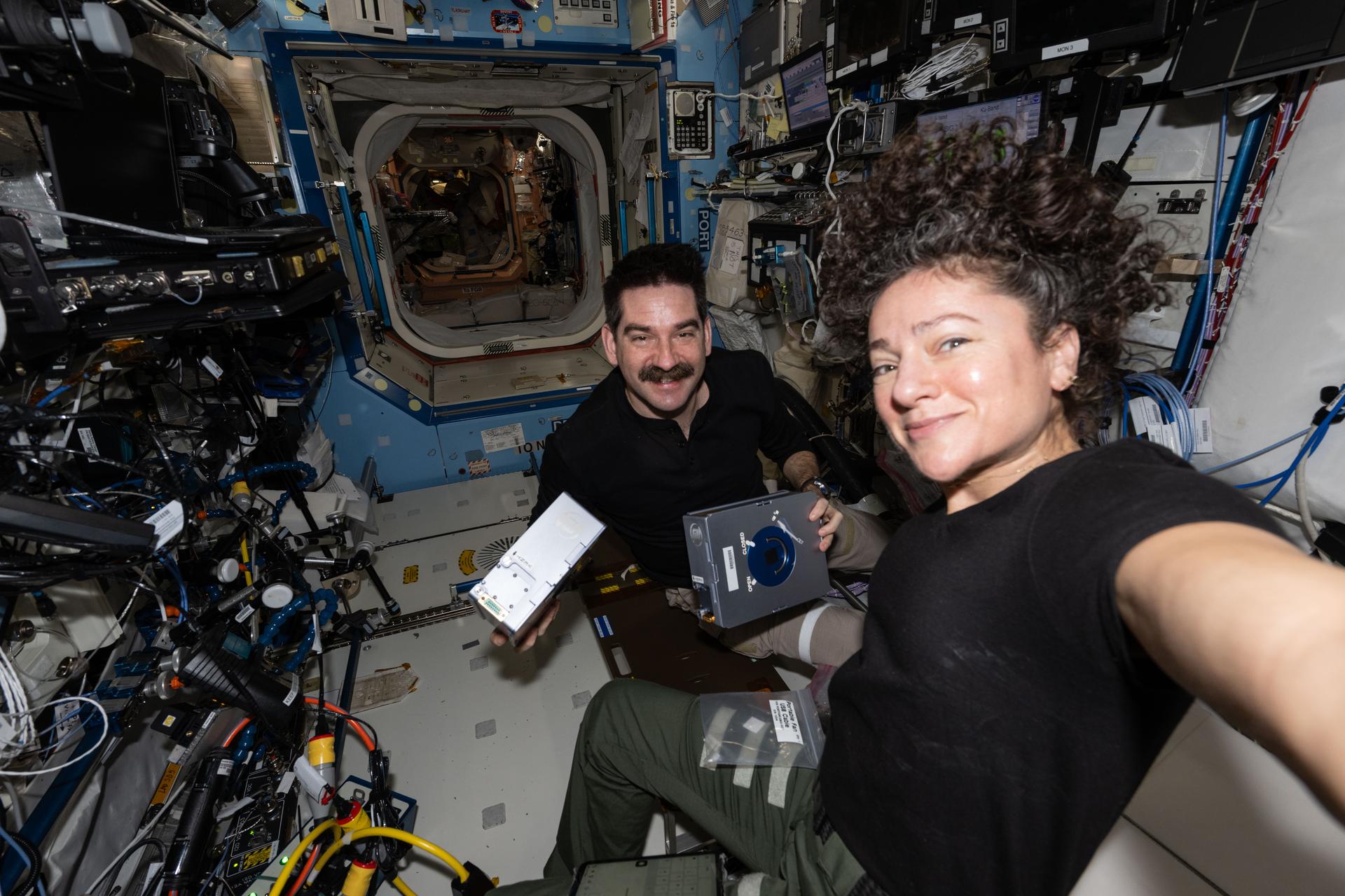NASA astronauts Jack Hathaway and Jessica Meir, both Expedition 74 flight engineers, pose together as Hathaway shows off a pair of Advanced Space Experiment Sample Processor-4 research cassettes being used aboard the International Space Station to study how weightlessness affects drug crystals possibly leading to new pharmaceutical formulas.