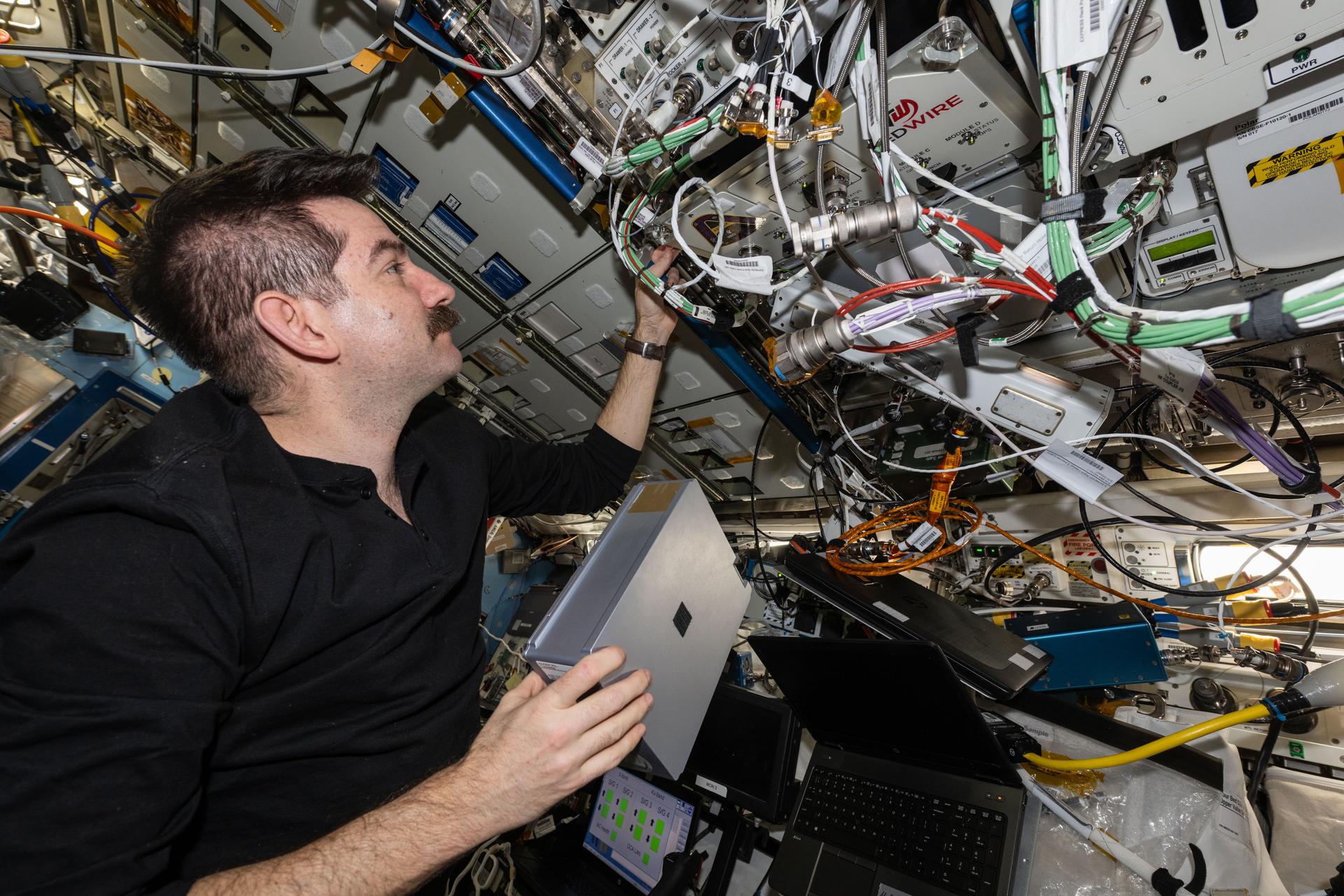 iss074e0604612 (May 22, 2026) --- NASA astronaut and Expedition 74 flight engineer Jack Hathaway prepares to install a research cassette into the Advanced Space Experiment Sample Processor-4 being used aboard the International Space Station to study how weightlessness affects drug crystals possibly leading to new pharmaceutical formulas. Credit: NASA/Jessica Meir
