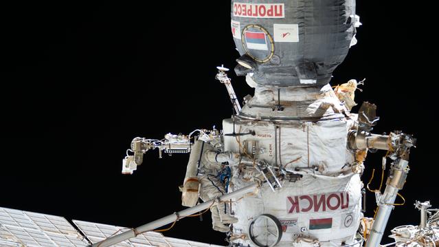 Cosmonaut Sergei Mikaev works outside the International Space Station's Poisk module in his Orlan spacesuit with blue stripes