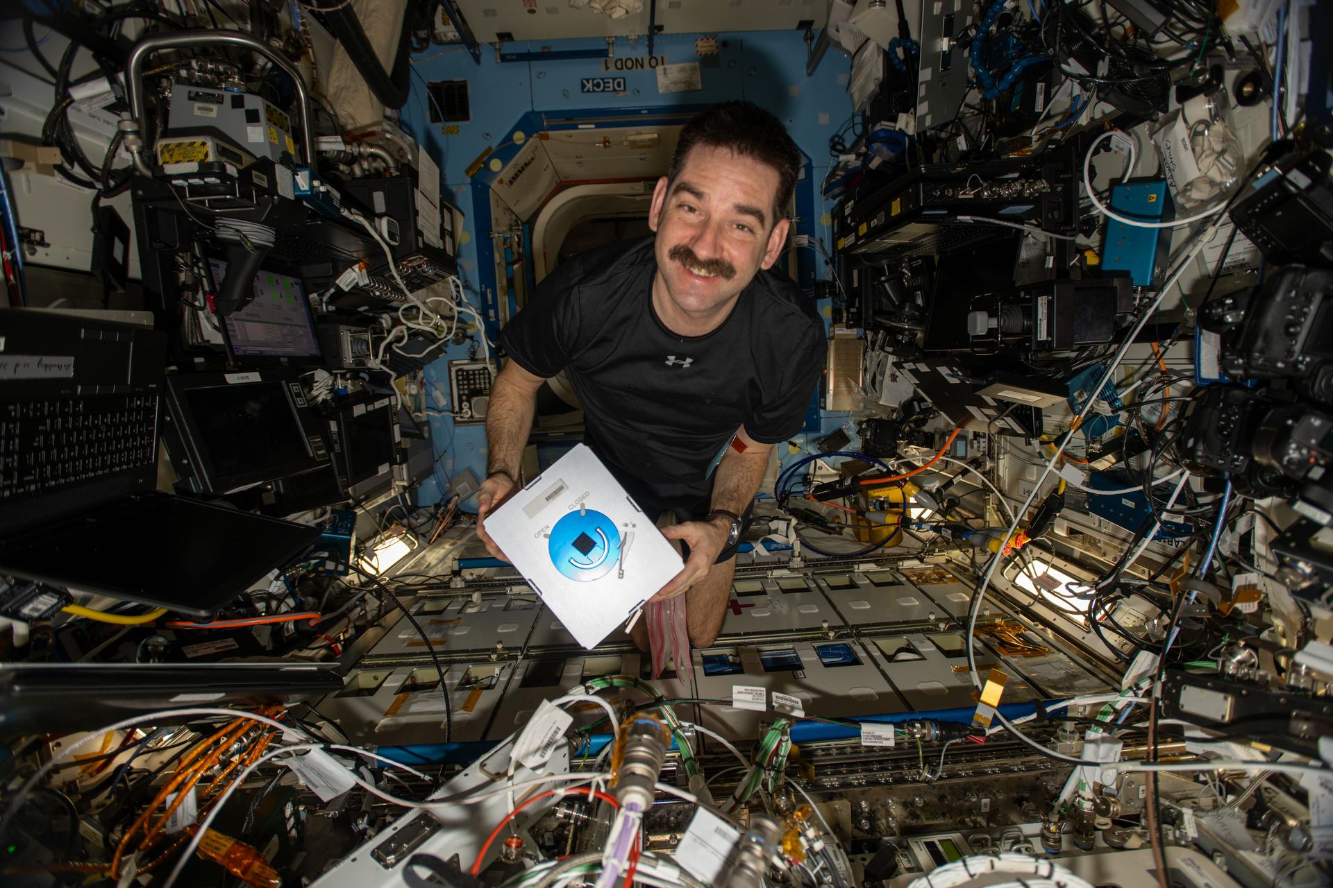 NASA astronaut and Expedition 74 flight engineer Jack Hathaway shows off an Advanced Space Experiment Sample Processor-4 research cassette being used aboard the International Space Station to study how weightlessness affects drug crystals possibly leading to new pharmaceutical formulas.