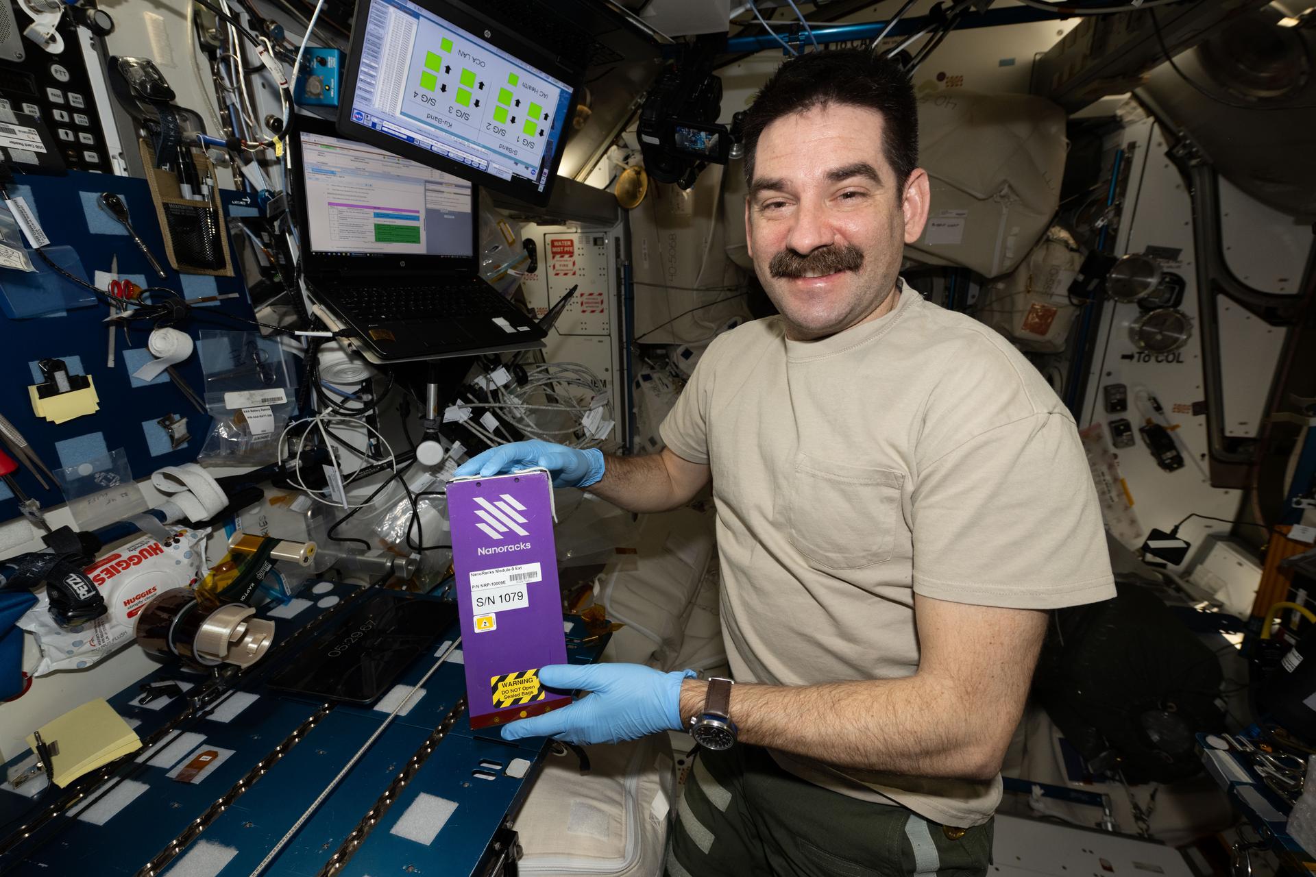 NASA astronaut and Expedition 74 flight engineer Jack Hathaway shows off NanoRacks research hardware that stored sample-containing tubes filled with seeds and microbes for a variety of student-designed experiments. Hathaway was activating the tubes aboard the International Space Station's Harmony module to expand the knowledge of space phenomena and inspire junior high and high school students to consider scientific, technical, and engineering careers.