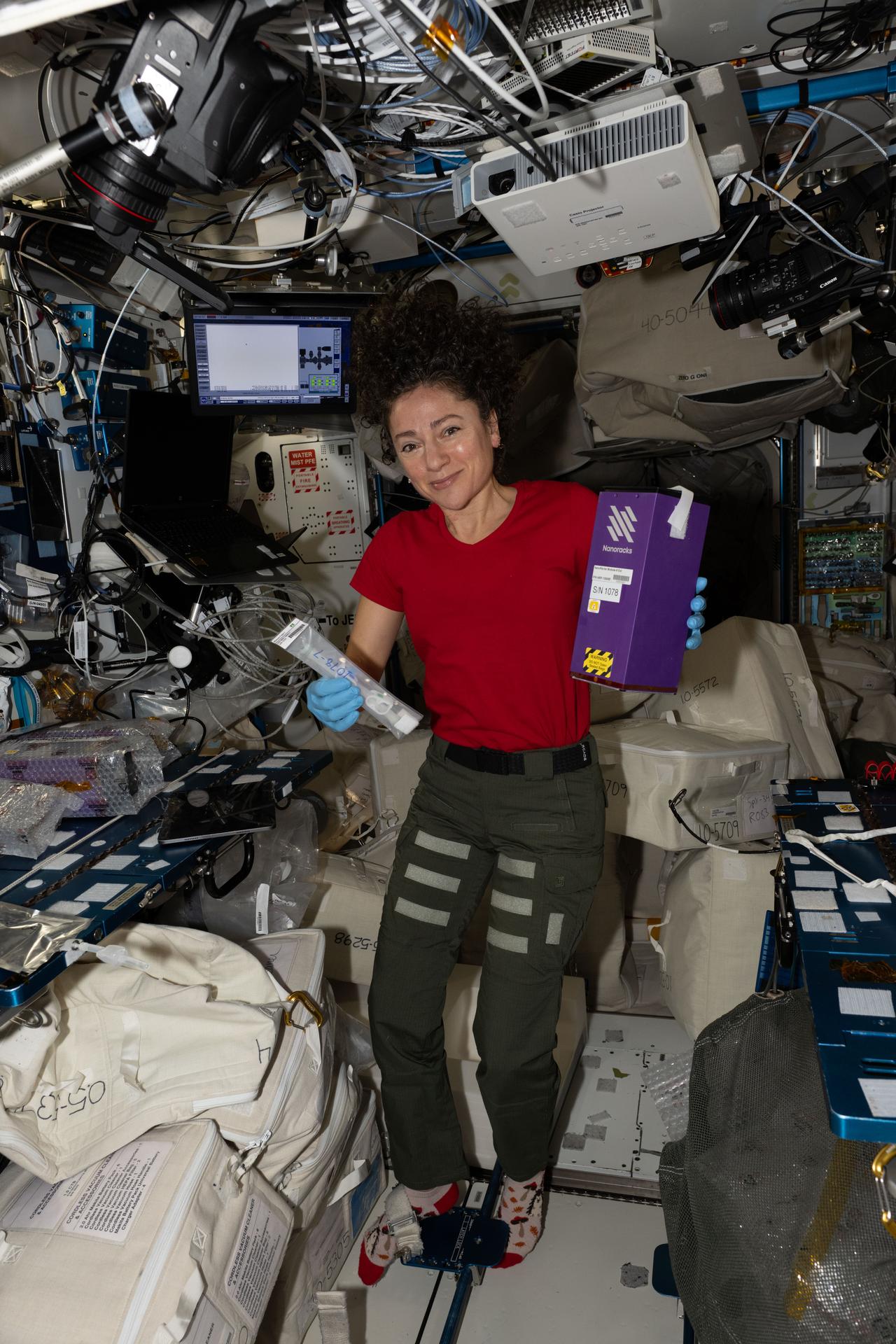 NASA astronaut and Expedition 74 flight engineer Jessica Meir activates tubes filled with microbial and botanical samples and shows off NanoRacks research hardware associated with a variety of student-designed experiments inside the International Space Station's Harmony module.