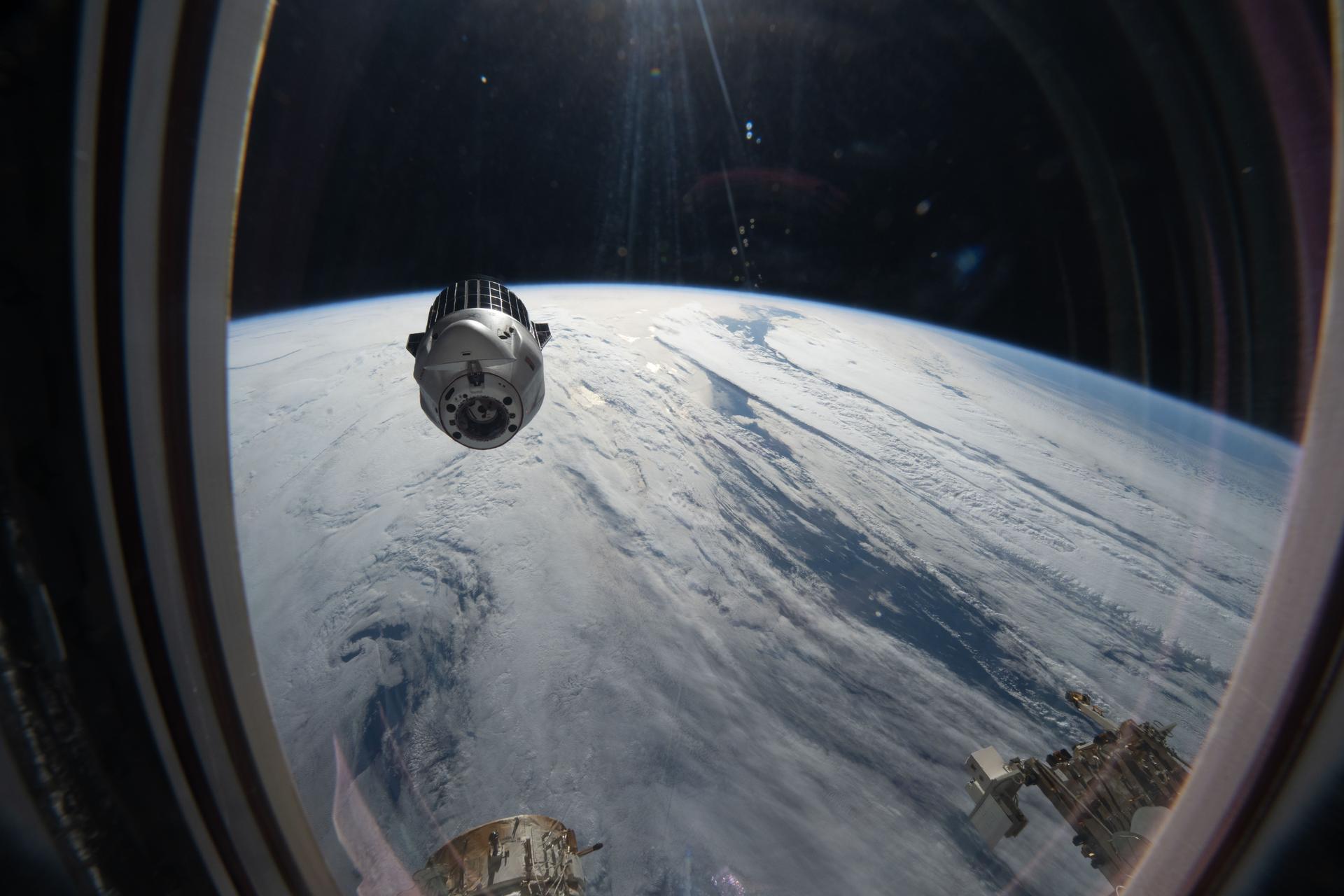 A SpaceX Dragon cargo spacecraft backs away from the International Space Station moments after undocking from the Harmony module's forward port while orbiting 265 miles above a cloudy North Pacific Ocean. Dragon, packed with completed science experiments and cargo for retrieval and analysis on Earth, parachuted to a splashdown off the coast of southern California the following day,