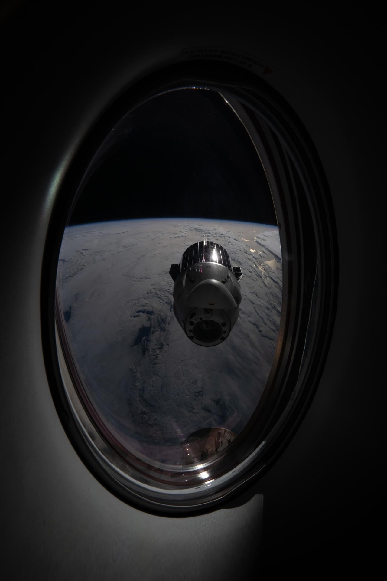 iss074e0750967 (June 16, 2026) --- This view looks out a window on a SpaceX Dragon crew spacecraft toward a departing SpaceX Dragon cargo spacecraft moments after it undocked from the International Space Station’s forward port on the Harmony module. The orbital outpost was soaring 265 miles above the North Pacific Ocean, off the coast of British Columbia, Canada, at the time of the photograph. Credit: ESA/Sophie Adenot