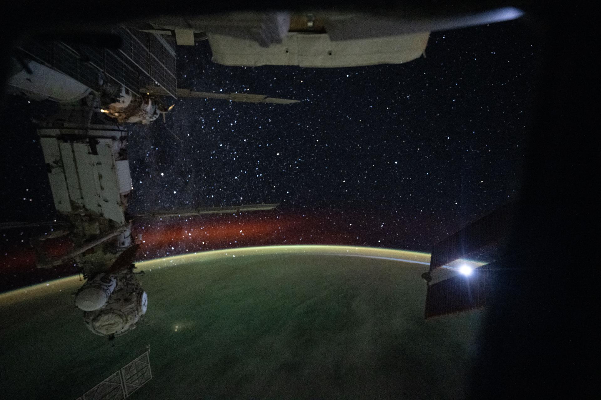 The International Space Station was soaring 262 miles above southern India at approximately 1:34 a.m. local time when this long‑duration photograph was taken, revealing a bright atmospheric glow and a starry night sky. At left is the Prichal module, attached to the Nauka science module on the orbital outpost’s Roscosmos segment.