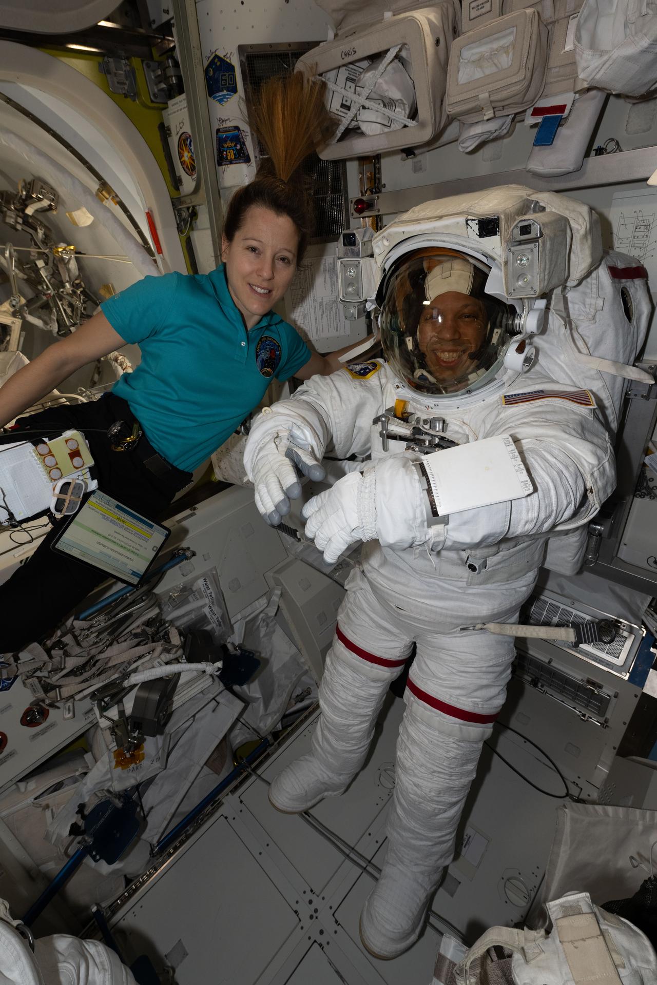 iss074e0760516 (June 23, 2026) --- Flight engineer Sophie Adenot of ESA (European Space Agency) assists flight engineer Chris Williams of NASA as he tries on his spacesuit, testing its comfort and mobility as well as its communications and life support systems inside the International Space Station’s Quest airlock. Williams was preparing for a spacewalk to replace a malfunctioning wrist joint on the Canadarm2 robotic arm, planned for June 30, 2026. Credit: NASA