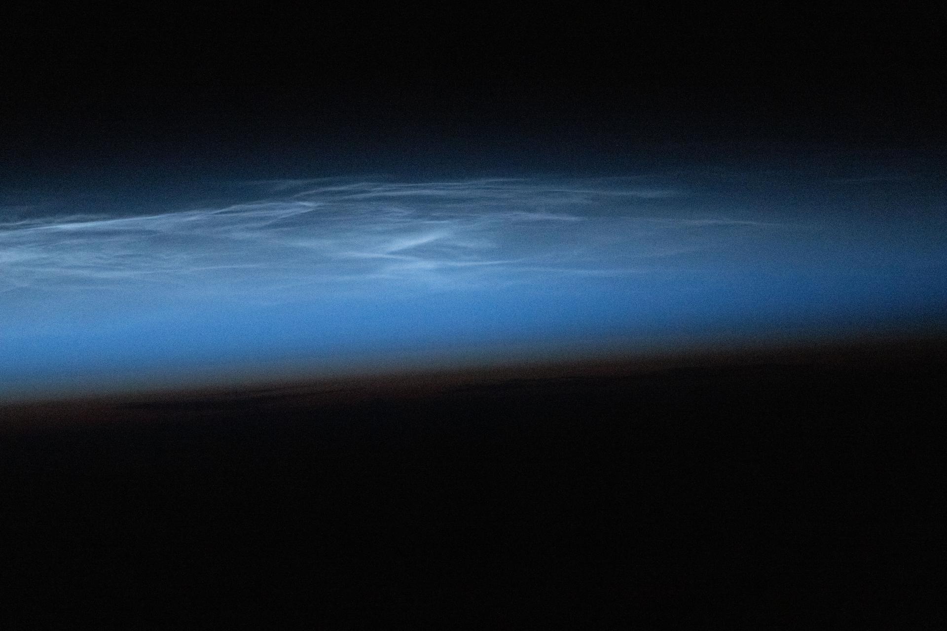 Noctilucent clouds—polar mesospheric clouds illuminated by sunlight just after the Sun has set below the horizon—are pictured from the International Space Station as it orbited 264 miles above northwest China. These high-altitude clouds are more easily seen from space than from the ground and form when extremely low temperatures freeze water vapor in the mesosphere during summer months at high latitudes.
