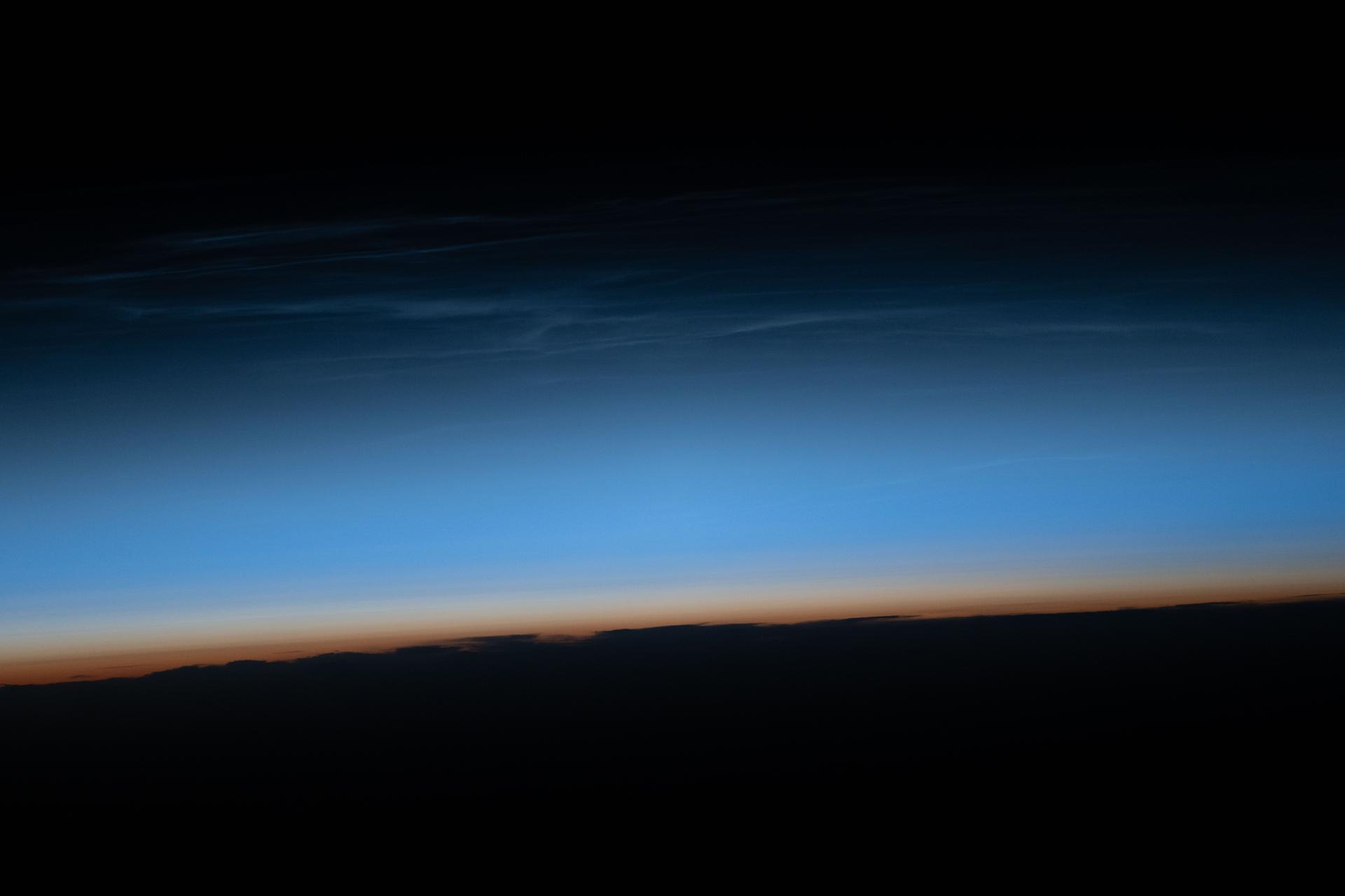 Noctilucent clouds—polar mesospheric clouds illuminated by sunlight just after the Sun has set below the horizon—are pictured from the International Space Station as it orbited 264 miles above northwest China. These high-altitude clouds are more easily seen from space than from the ground and form when extremely low temperatures freeze water vapor in the mesosphere during summer months at high latitudes.