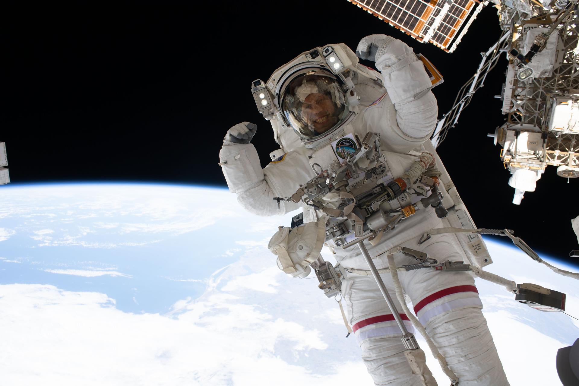 NASA astronaut and Expedition 74 flight engineer Chris Williams playfully flexes for a portrait during a seven‑hour‑and‑20‑minute spacewalk to replace a malfunctioning wrist joint on the International Space Station’s Canadarm2 robotic arm.