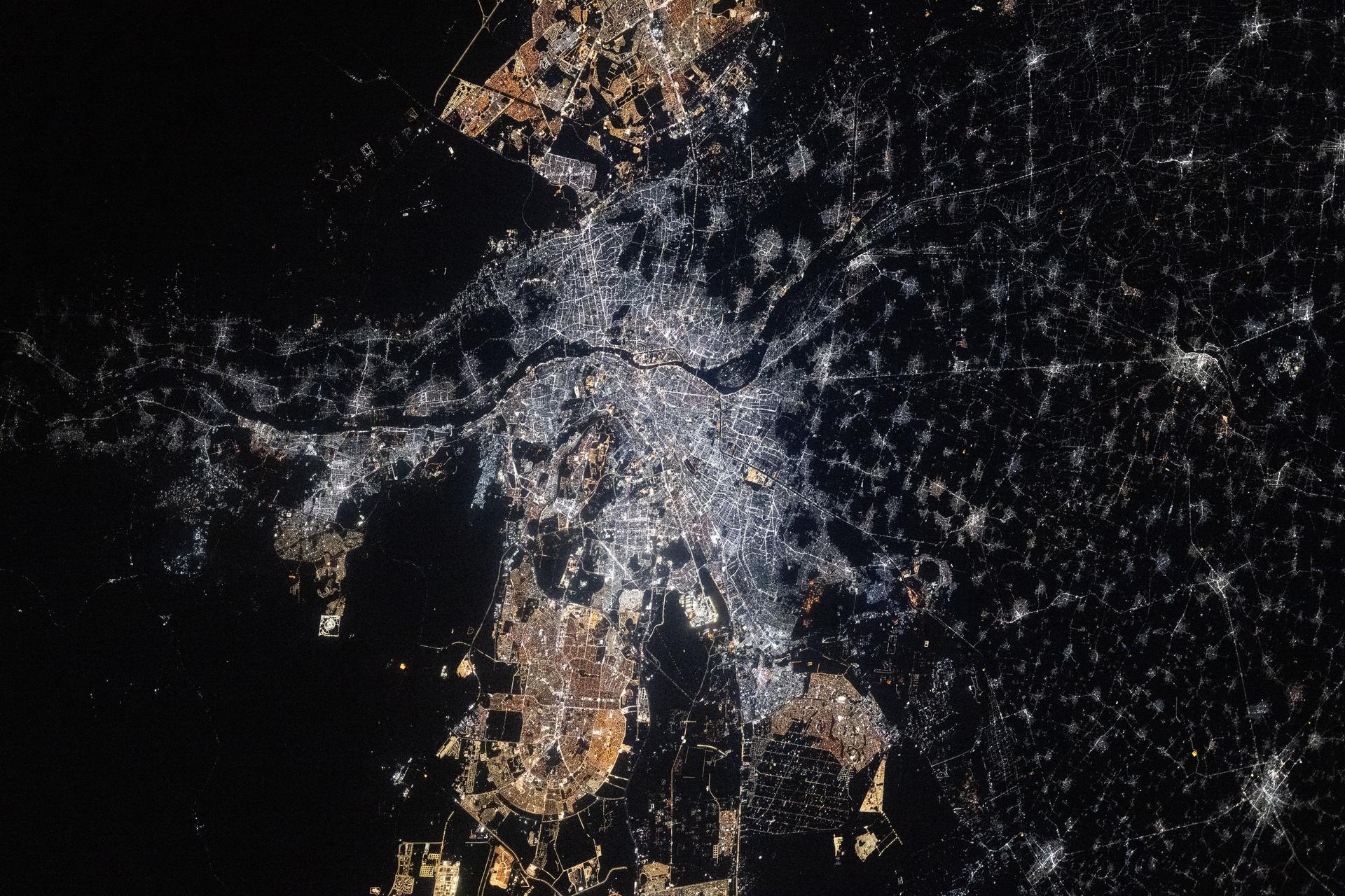 Cairo, Egypt, and its surrounding metropolitan area—with a population of about 22 million—is split by the Nile River and sits at the base of the Nile Delta. Cairo’s major urban districts (center) use newer LED fixtures that emit bright white light, while the suburban areas (top and bottom) use older high‑pressure sodium (HPS) lamps that produce a warm amber glow. The International Space Station was orbiting 262 miles above Earth at approximately 11:05 p.m. local time when this photograph was taken.