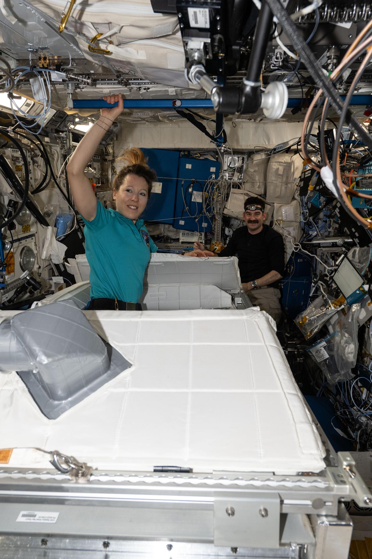 Expedition 74 flight engineers Sophie Adenot of ESA (European Space Agency) and Jack Hathaway of NASA (background) are pictured inside the International Space Station's Columbus laboratory module. The astronauts were upgrading a temporary sleep station, also called the Crew Alternate Sleep Accommodation (CASA), aboard Columbus. CASA modifications include a better fit for crew members, improved airflow velocity, an updated lighting configuration, and upgraded side panels and interior liners.