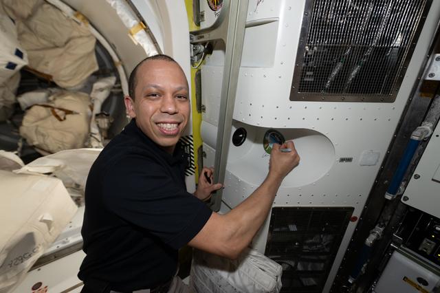 NASA astronaut Chris Williams signs his autograph inside the International Space Station