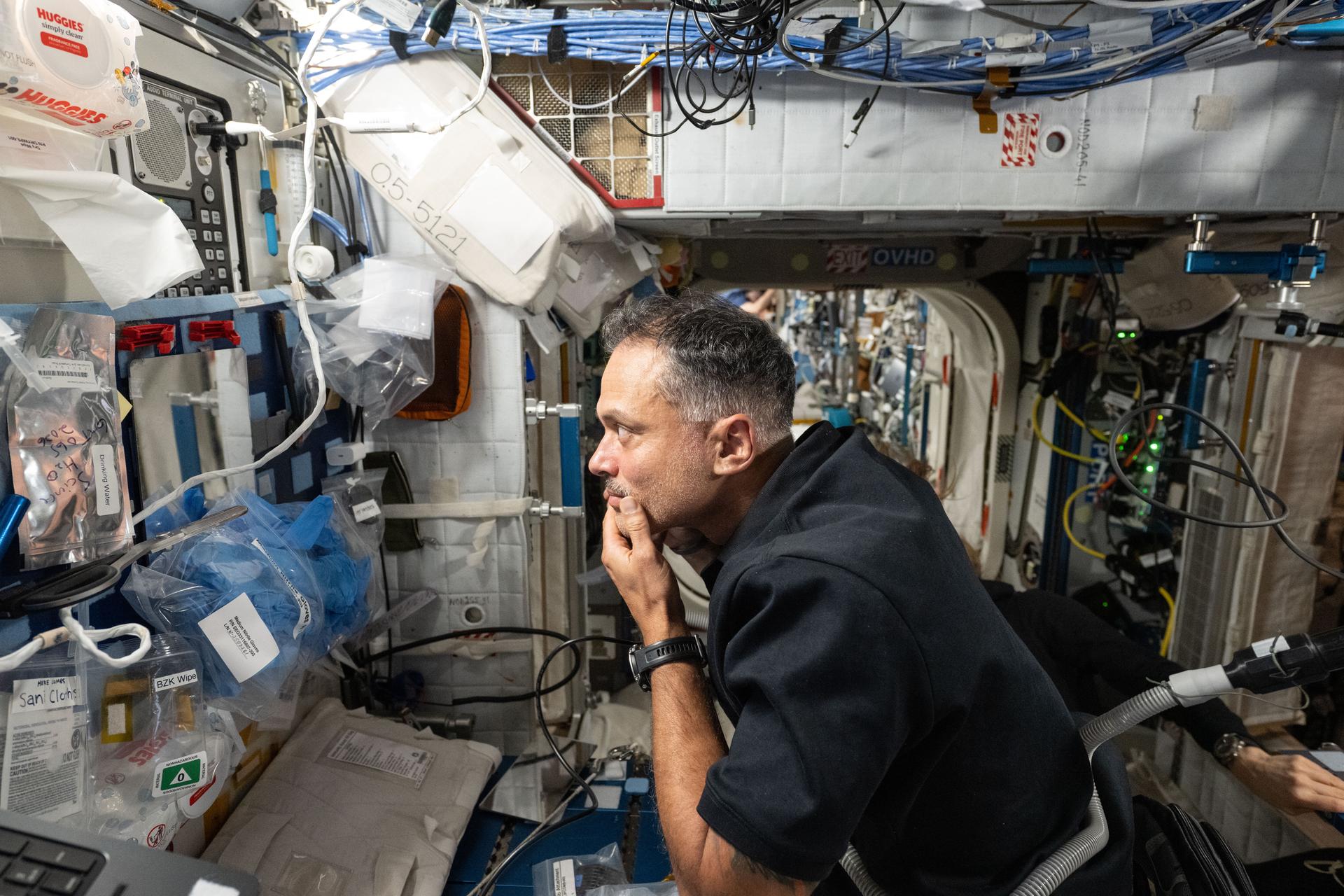 iss074e0831856 (July 23, 2026) --- NASA astronaut and Expedition 74 flight engineer Anil Menon looks at himself in a mirror after a shave aboard the International Space Station. The astronauts use an electric razor attached to a vacuum that collects loose clippings to keep the orbital outpost’s atmosphere clean in microgravity. Credit: NASA/Chris Williams