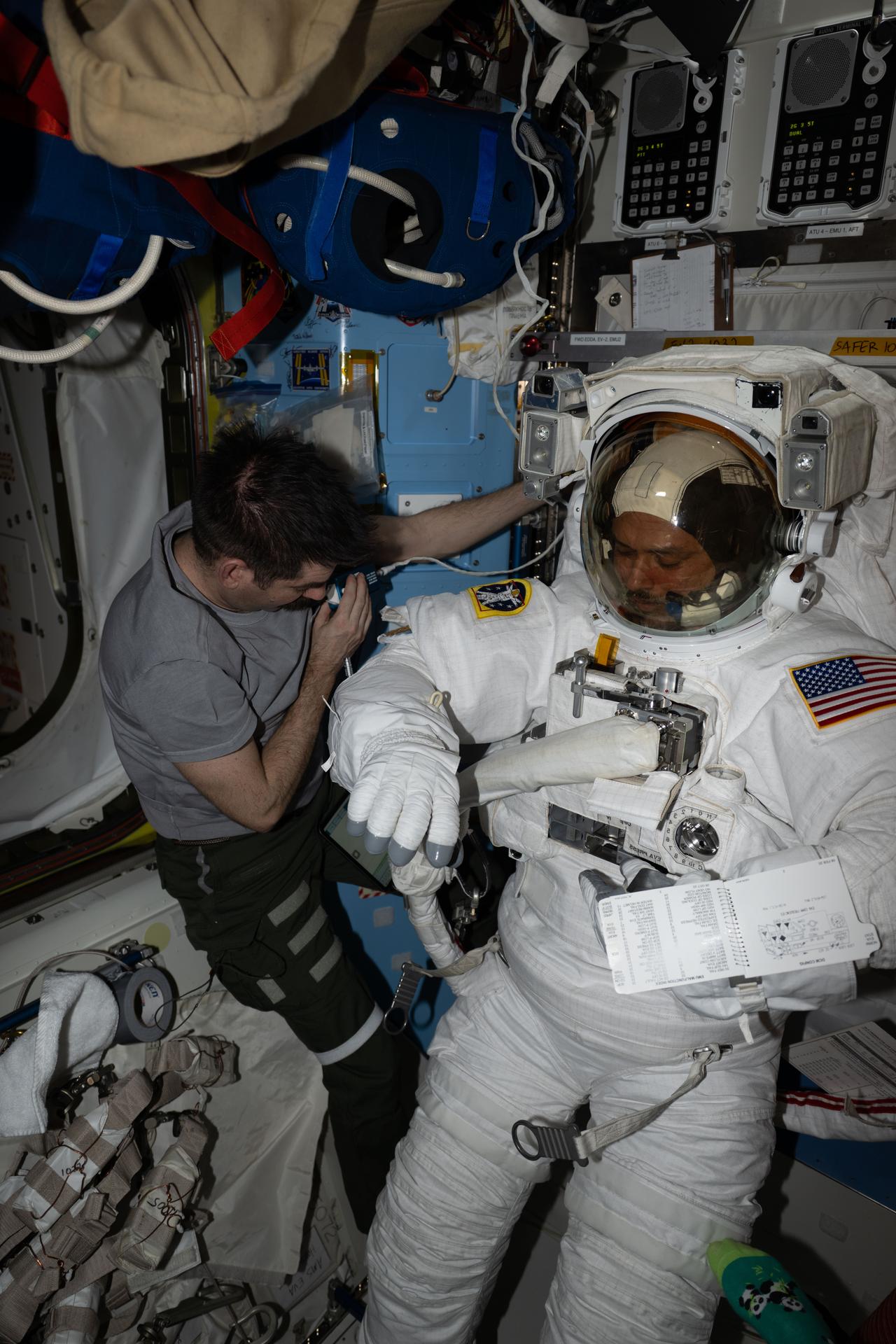 iss075e0000132 (Aug. 4, 2026) --- Expedition 75 flight engineer Jack Hathaway assists Expedition 75 flight engineer Anil Menon, both NASA astronauts, inside the Quest airlock as he tried on a spacesuit to verify its comfort, mobility, and functionality. Menon was conducting an on-orbit fit verification of the suit before conducting his first spacewalk outside of the International Space Station. Credit: NASA/Jessica Meir