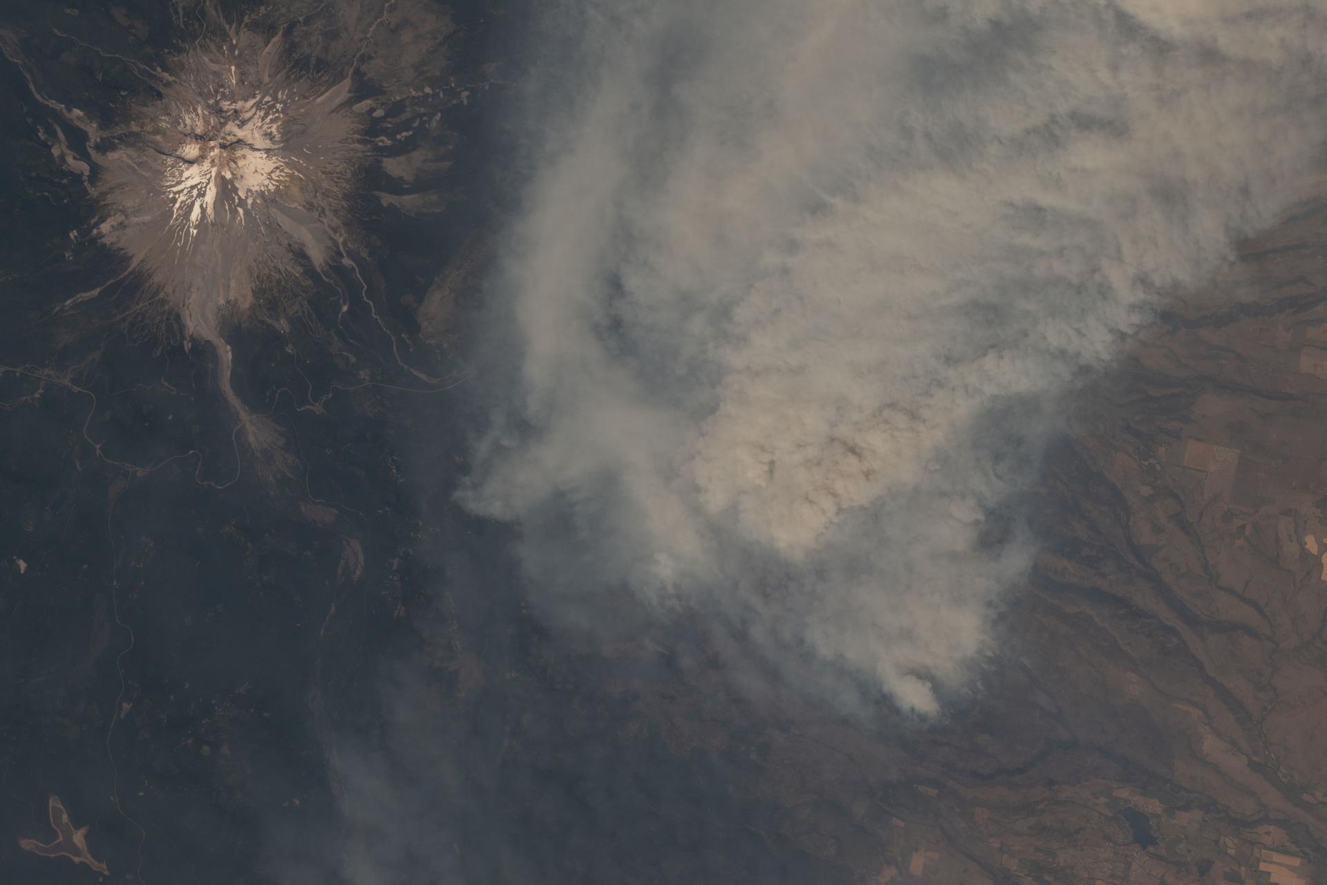 Thick smoke emanates from the Grasshopper wildfire burning near Mount Hood (upper left) in the state of Oregon. The International Space Station was orbiting 262 miles above the northwestern United States at the time of this photograph.