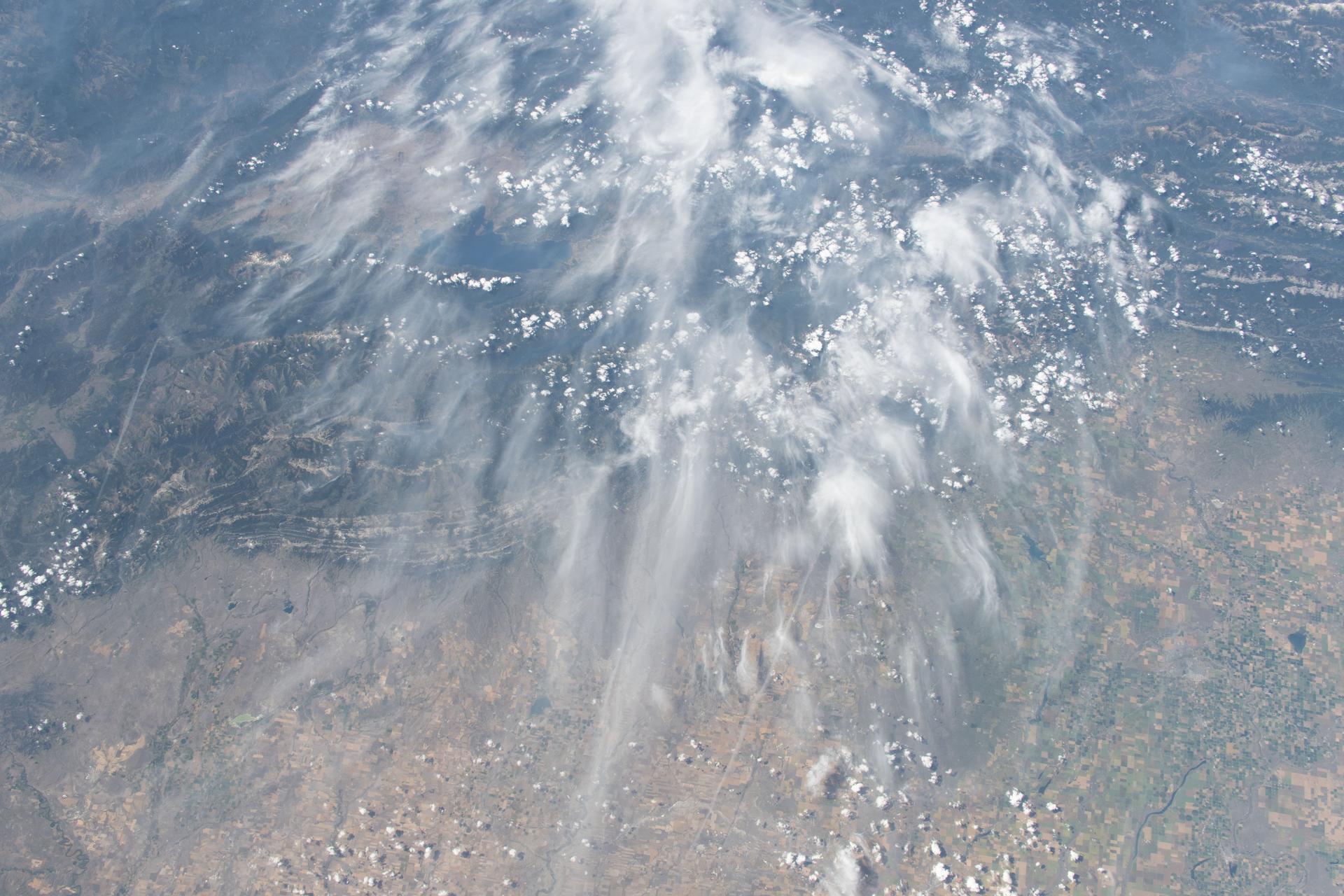 Smoke from wildfires drifts among the clouds above Montana's northwestern landscape in this photograph from the International Space Station as it orbited 262 miles above North America.