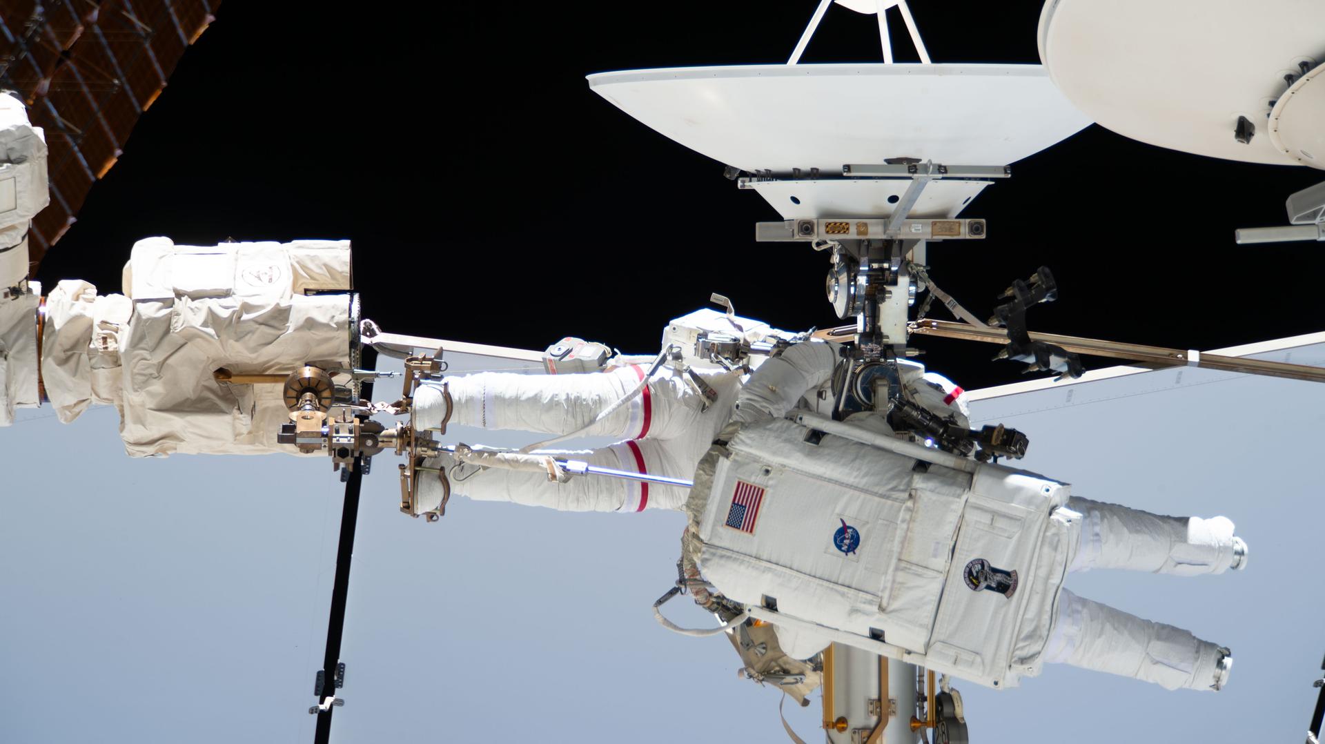 From left, Expedition 75 flight engineers Anil Menon of NASA (partially obscured and wearing the spacesuit with a red stripe on the legs) and Sophie Adenot of ESA (European Space Agency) work together during a six‑hour and 23‑minute spacewalk outside the International Space Station. The duo disconnected a failed high‑speed antenna and secured it with a long‑duration tie‑down on the orbital outpost’s Z1 truss segment. A spare antenna will be installed on the Z1 truss during a future spacewalk.