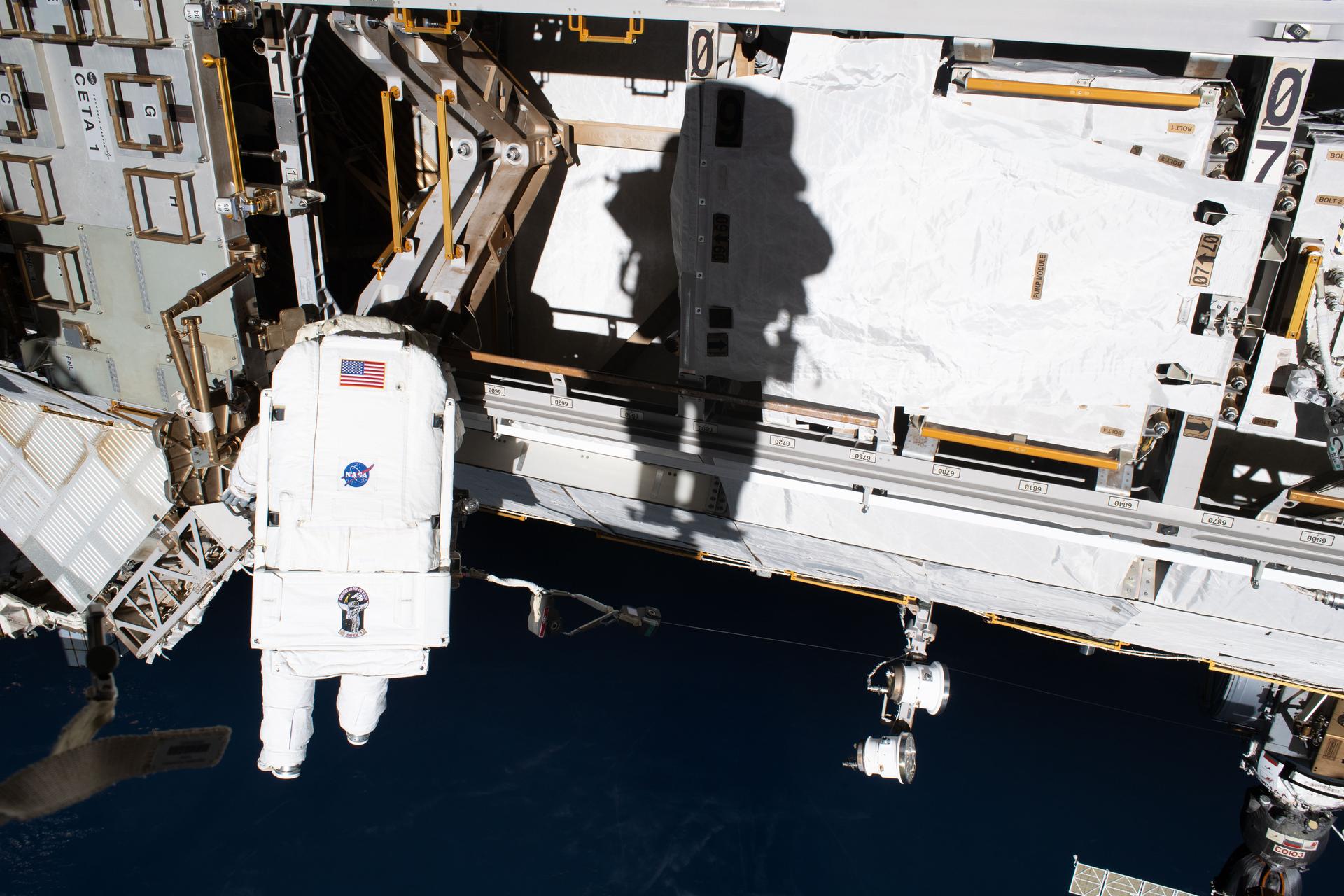 ESA (European Space Agency) astronaut and Expedition 75 flight engineer Sophie Adenot is pictured tethered to the International Space Station, while the shadow of NASA astronaut and Expedition 75 flight engineer Anil Menon is cast on a truss segment. Menon took this photograph with the sun at his back during a six-hour and 30-minute spacewalk to install a high-speed space-to-ground antenna on the orbital outpost.