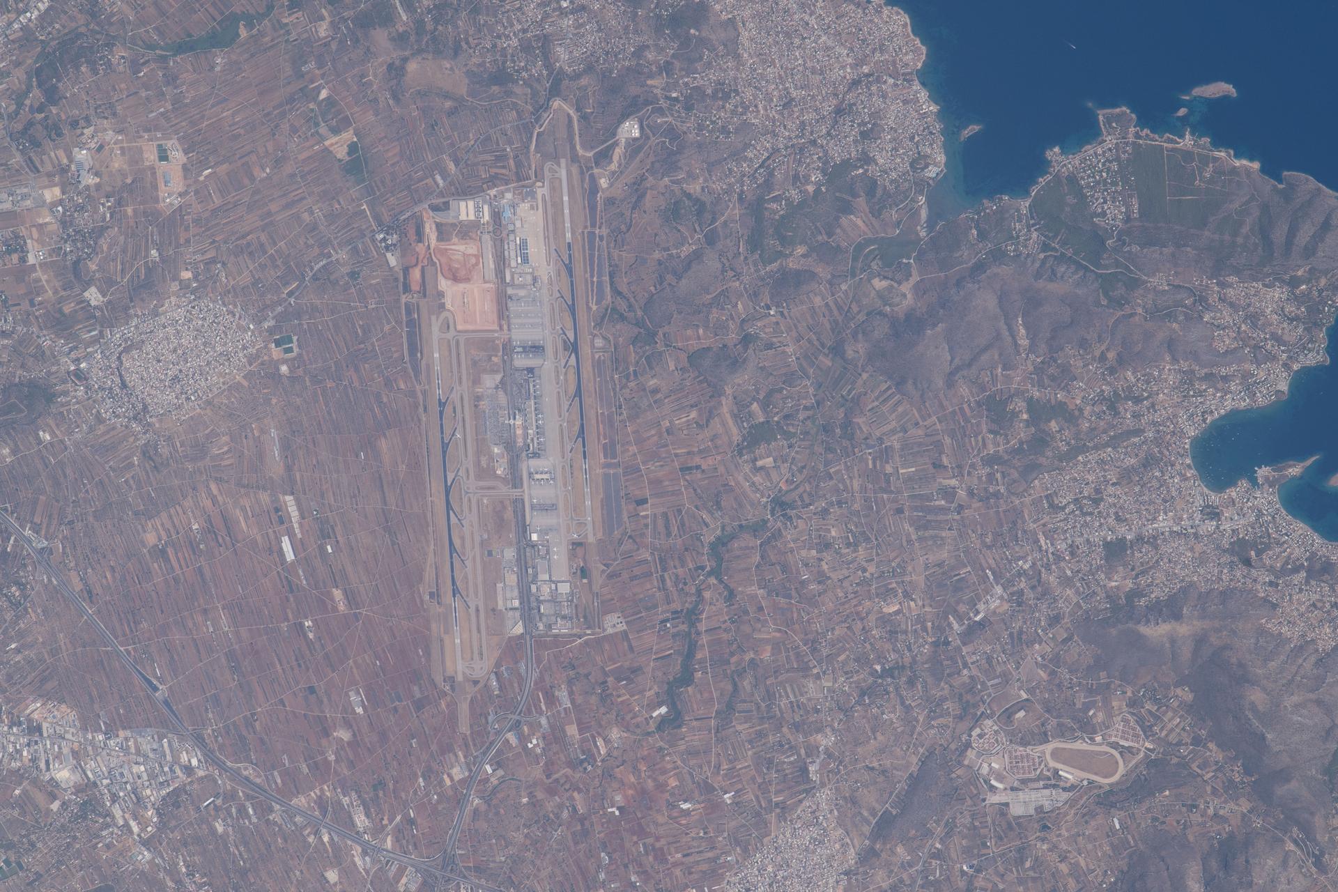 Athens International Airport, southeast of Athens, Greece, near the Aegean Sea, handled nearly 35 million passengers in 2025. The International Space Station was orbiting 261 miles above Europe when this photograph was taken.