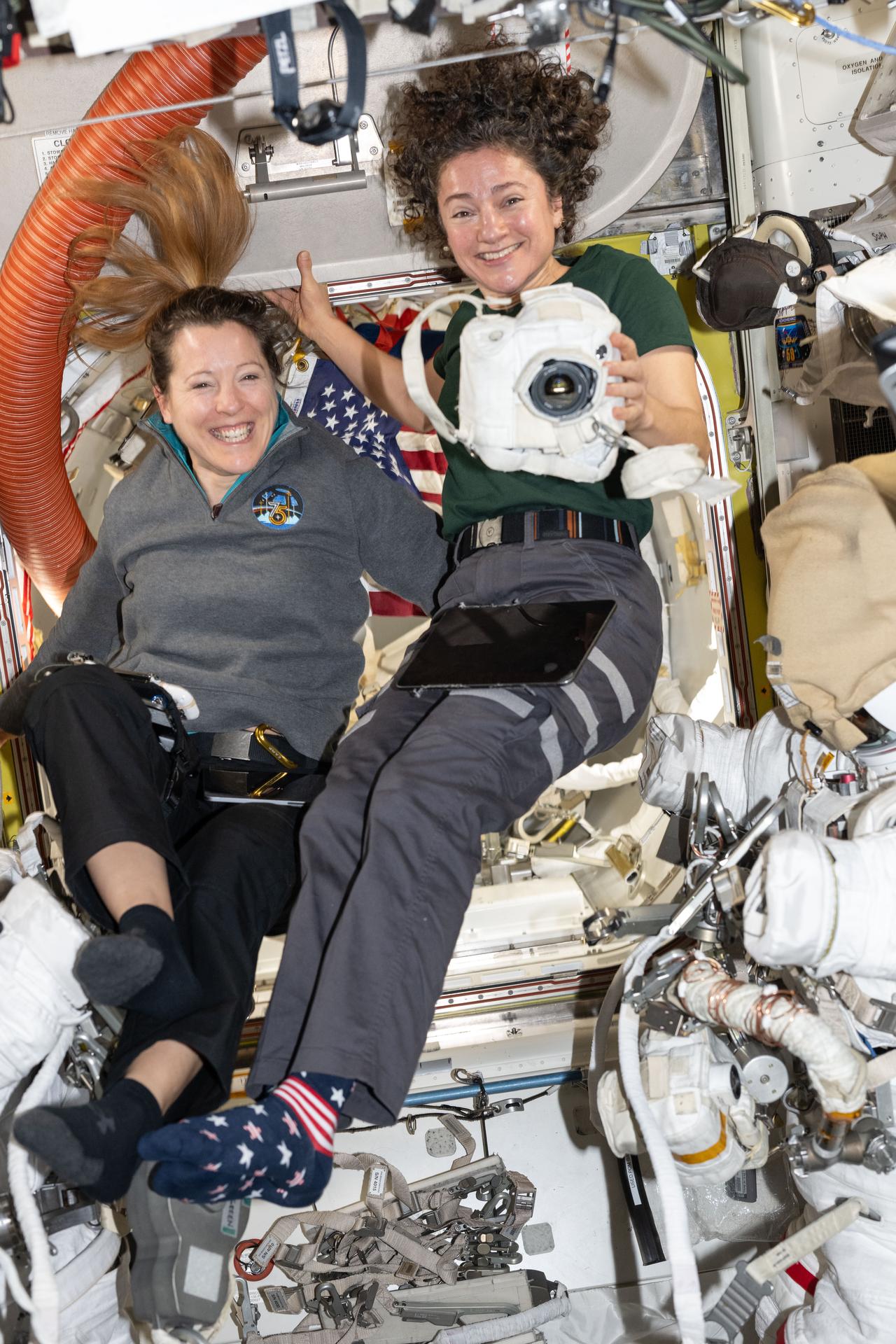 From left, Expedition 75 crewmates Sophie Adenot of ESA (European Space Agency) and Jessica Meir of NASA, flight engineer and station commander respectively, smile for a portrait while working together inside the International Space Station’s Quest airlock. Meir is holding a camera covered in a protective thermal blanket that shields it from space radiation, as the two astronauts prepare spacesuits and tools for a spacewalk they conducted together on Sept. 1.