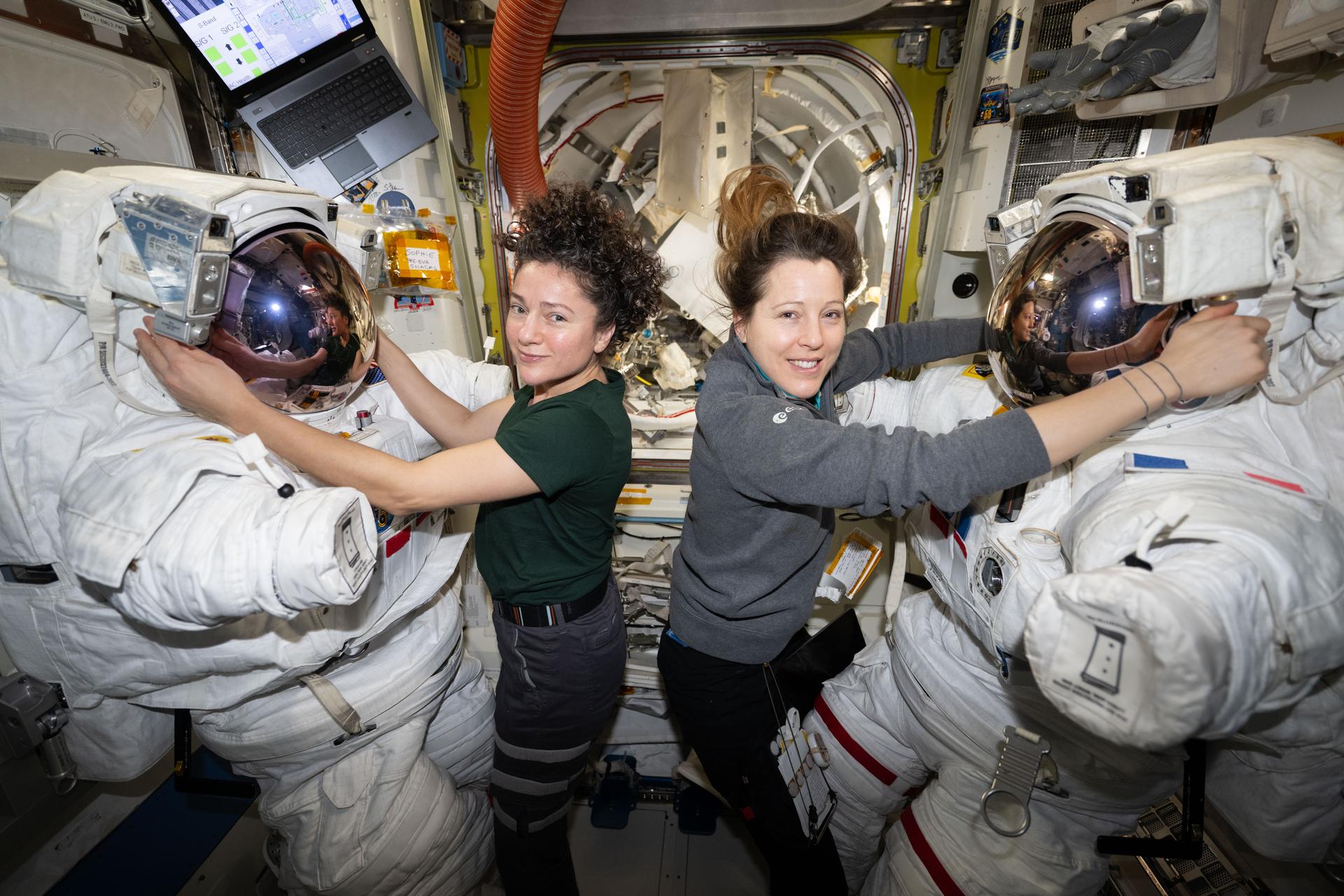 From left, astronauts Jessica Meir of NASA and Sophie Adenot of ESA (European Space Agency) pose for a portrait inside the International Space Station’s Quest airlock while configuring spacesuits the day before they conducted a spacewalk together. Meir and Adenot spent six hours and 49 minutes the next day installing a spacecraft navigation aid, swabbing the station’s exterior for microorganisms, and preparing a cosmic particle detector for future upgrades outside the International Space Station.
