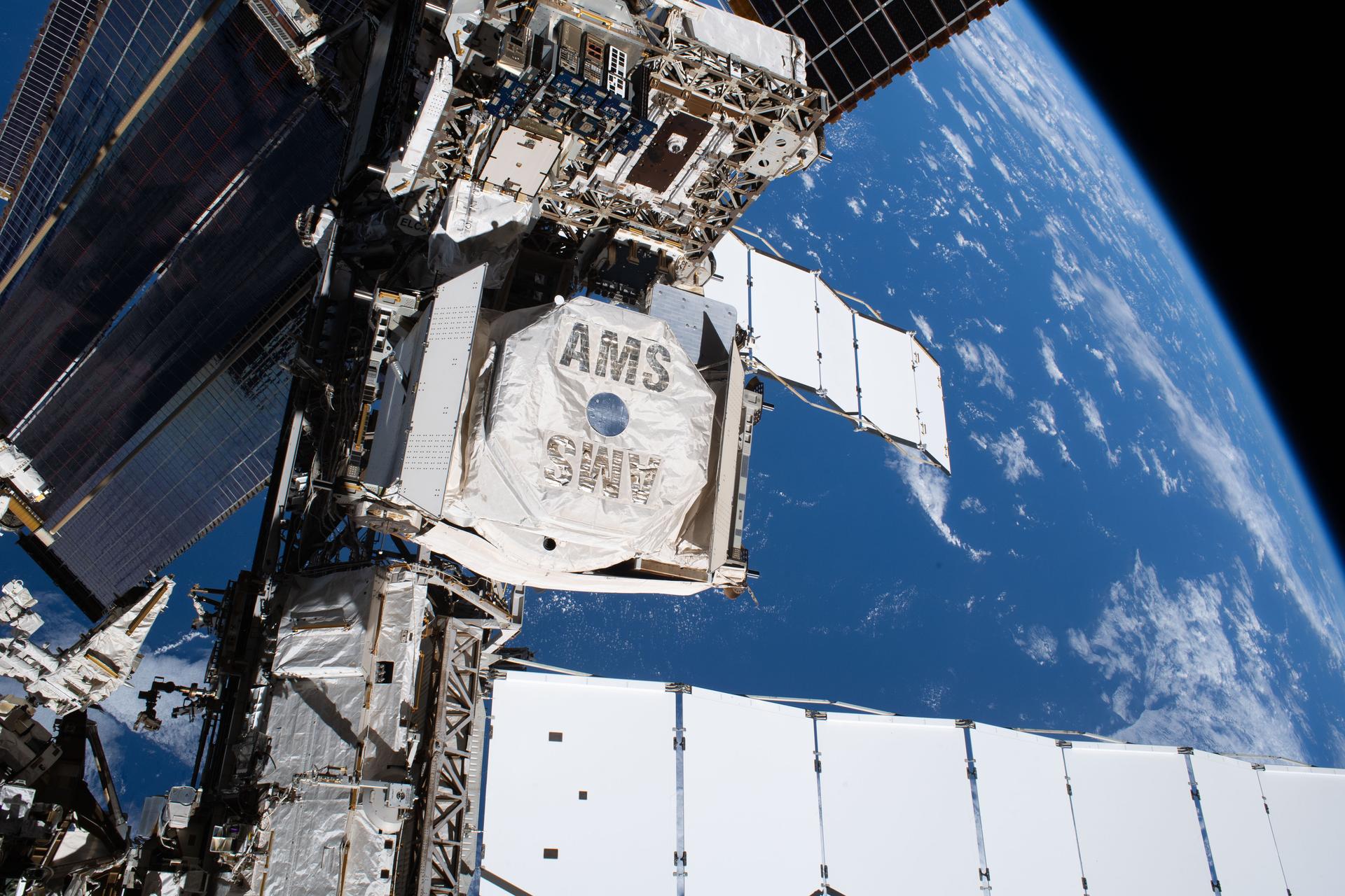 The Alpha Magnetic Spectrometer (AMS), a cosmic particle detector, is pictured on the International Space Station’s starboard truss structure. The AMS uses the microgravity environment to advance knowledge of the universe, potentially leading to a better understanding of its origin by searching for antimatter, dark matter, and measuring cosmic rays.