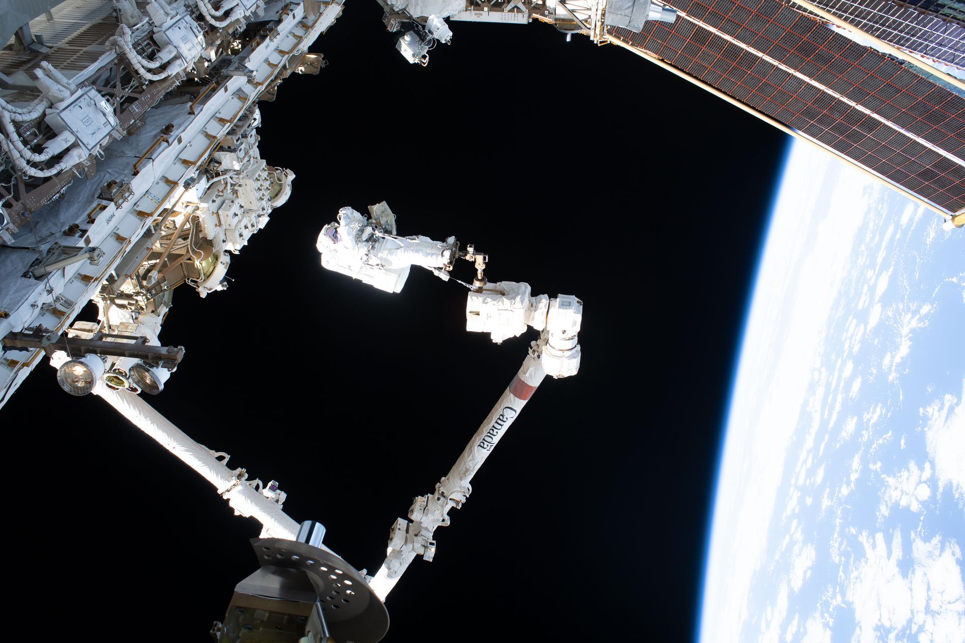 iss075e0086496 (Sept. 1, 2026) --- Expedition 75 commander Jessica Meir of NASA rides the Canadarm2 robotic arm during a spacewalk for navigation and science maintenance outside the International Space Station. Meir was attached to an articulating portable foot restraint installed on Canadarm2’s latching end effector. The orbital outpost was soaring 259 miles above the Pacific Ocean southwest of Mexico when this photograph was taken. Credit: NASA