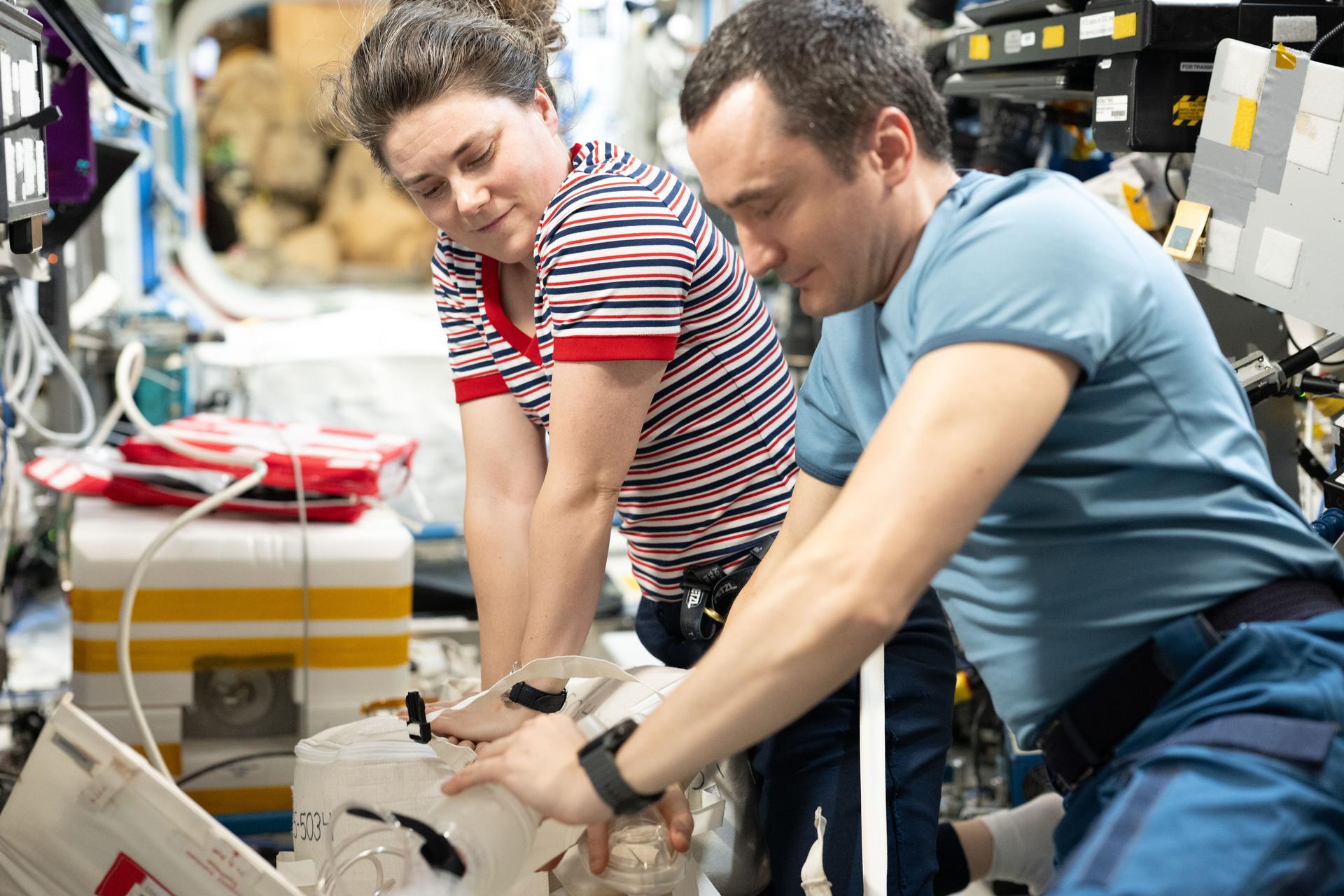 Expedition 75 flight engineers Anna Kikina and Pyotr Dubrov, both Roscosmos cosmonauts, practice CPR in the weightless environment of the International Space Station. Conducting chest compressions in microgravity requires securing the patient with restraints while the crew member braces their feet against a fixed surface to generate effective force.