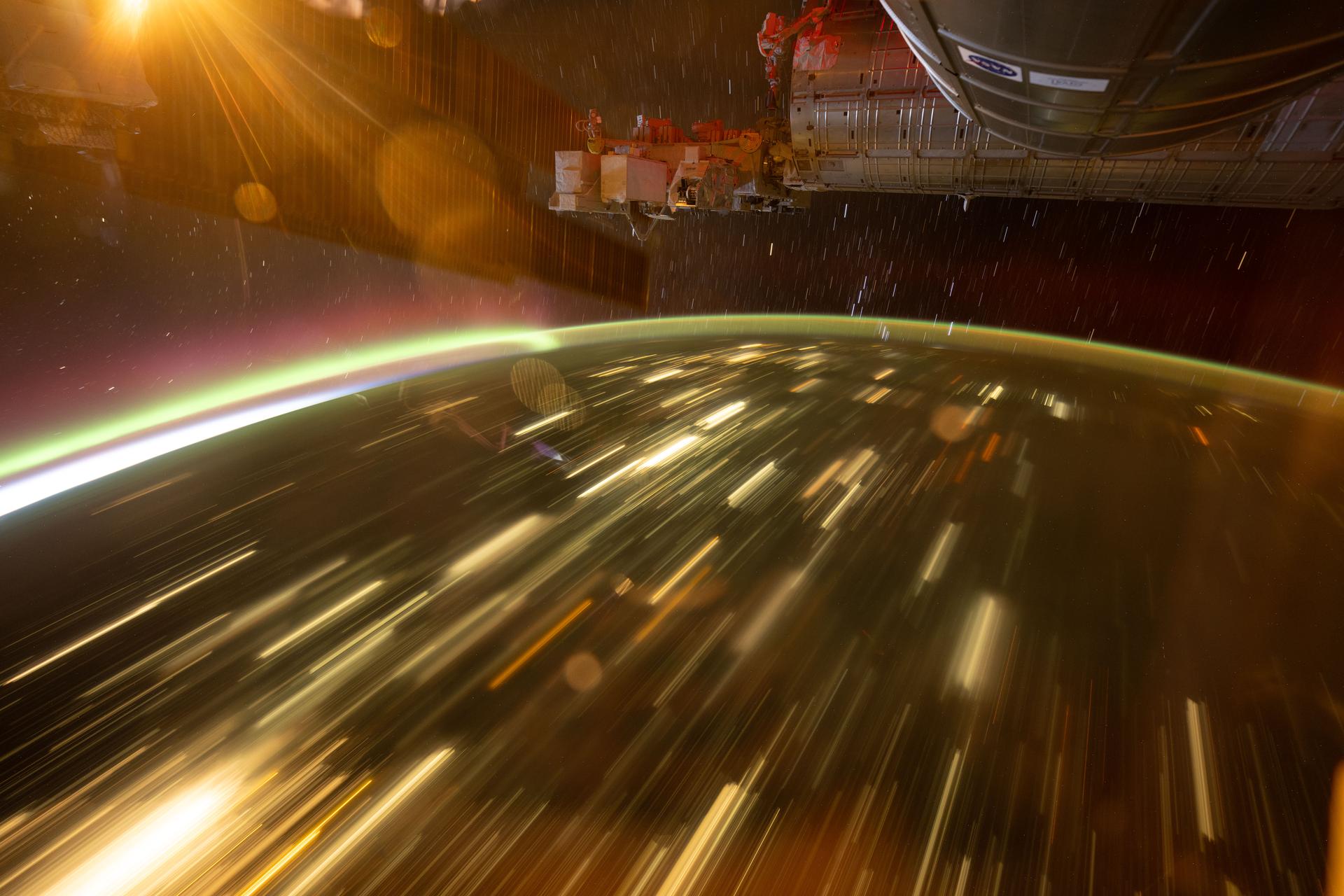 This long-duration image shows star trails above Earth, an aurora arcing across the atmosphere, and the city lights of Central Asia stretching below the International Space Station as it orbited 262 miles above Earth.