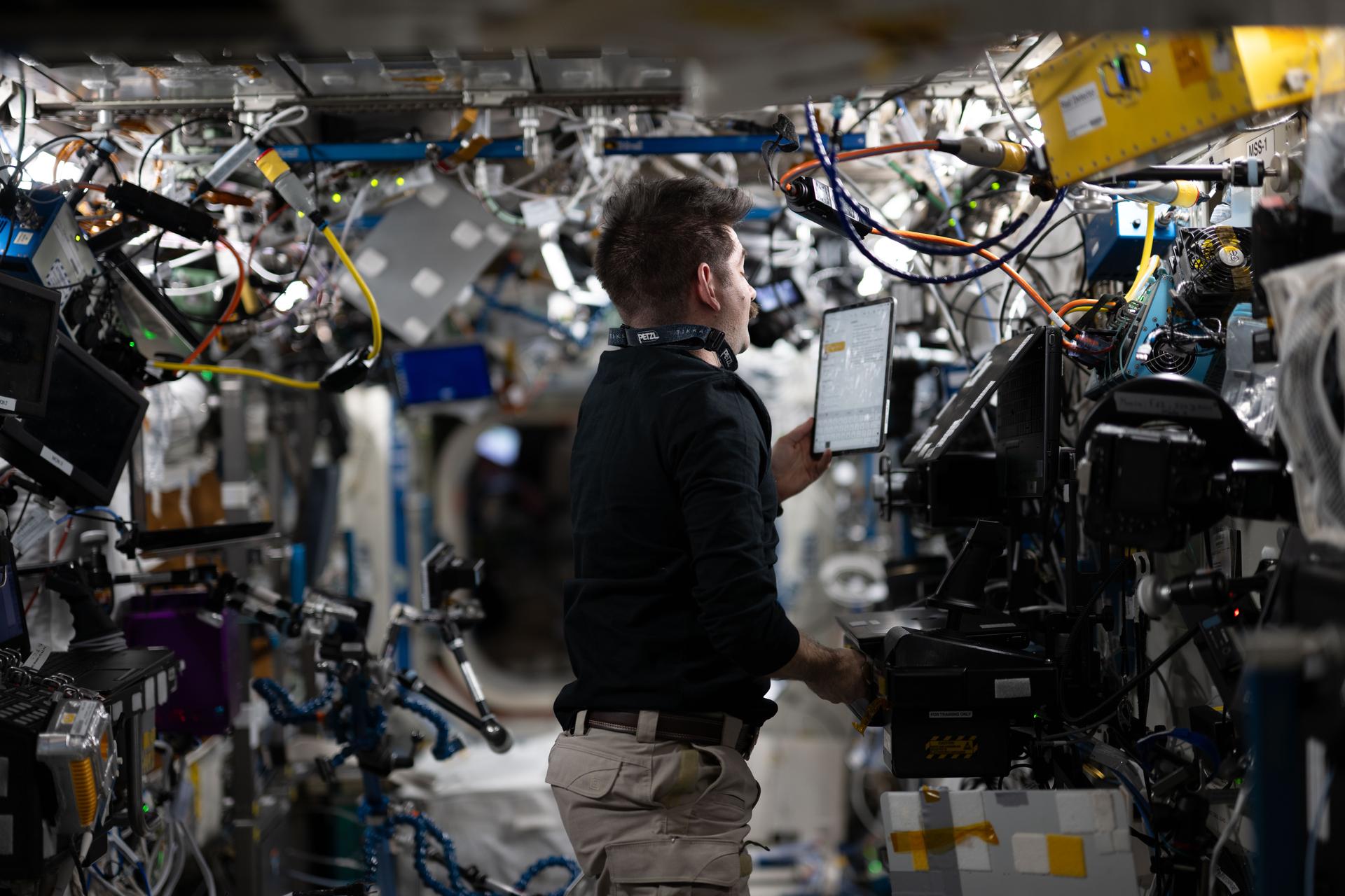 NASA astronaut and Expedition 75 flight engineer Jack Hathaway checks procedures on a computer tablet while working inside the International Space Station's Destiny laboratory module.